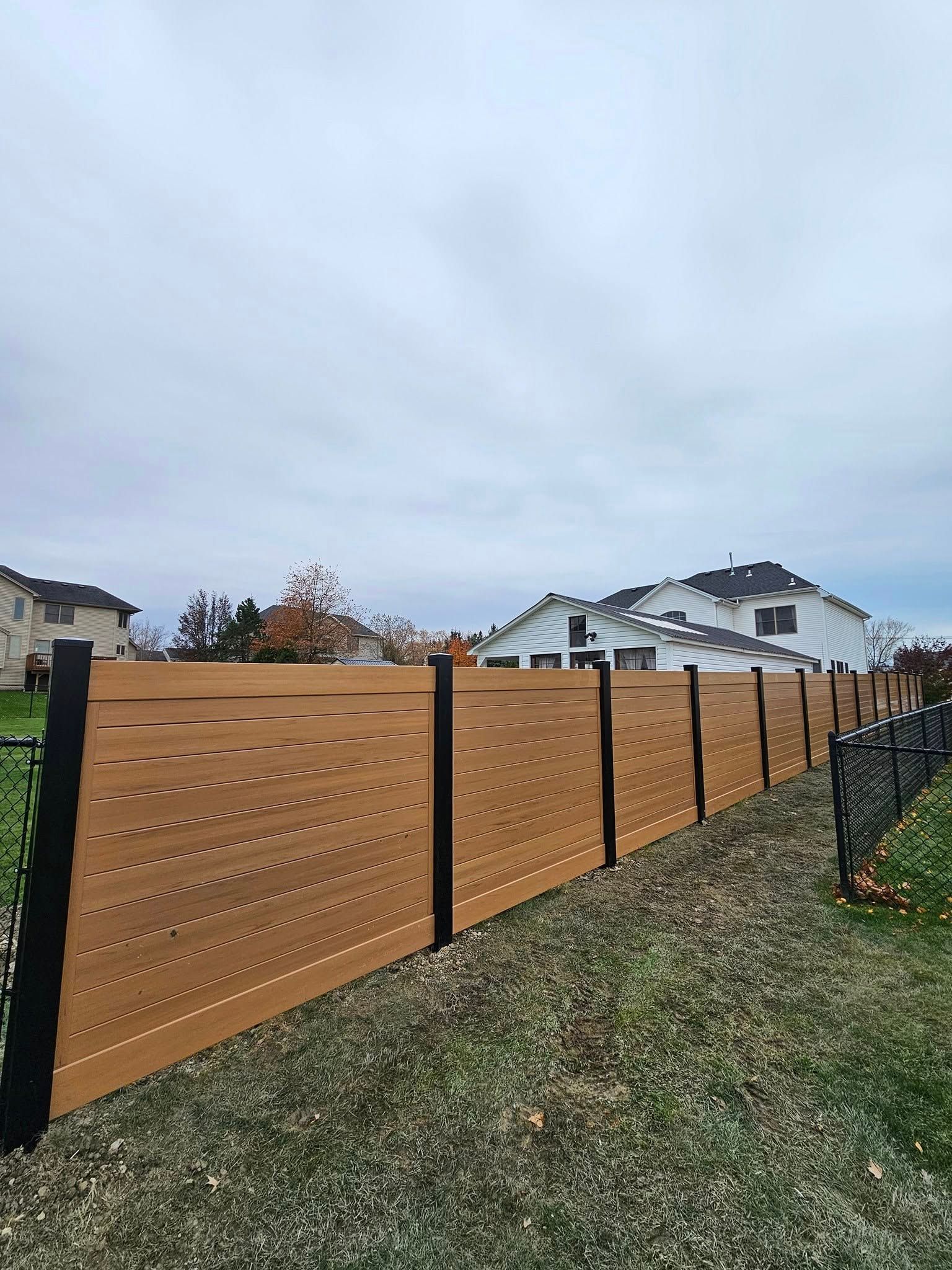 White front gate and fence beside a paved path under a blue sky in a suburban yard