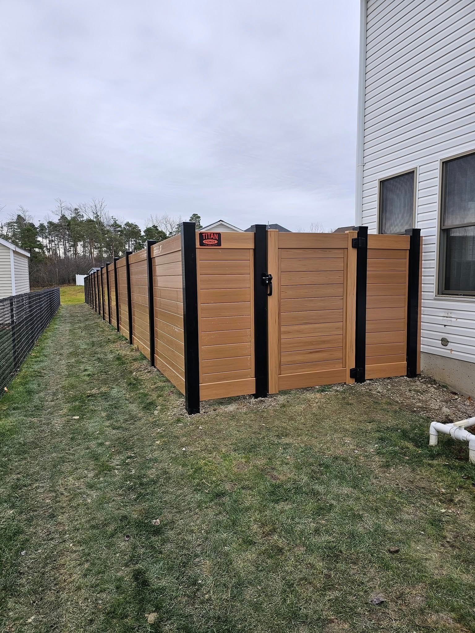 Wooden privacy fence panels lined beside a white building on a grassy yard