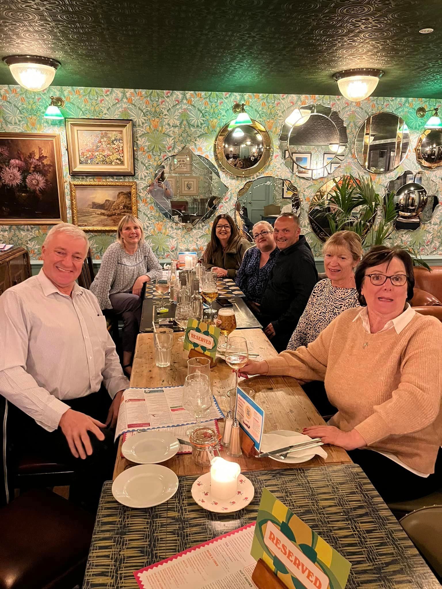 A group of people are sitting at a long table in a restaurant.