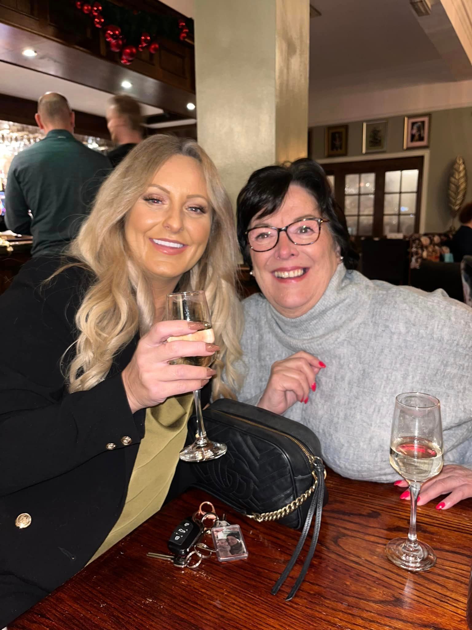 Two women are sitting at a table holding wine glasses.