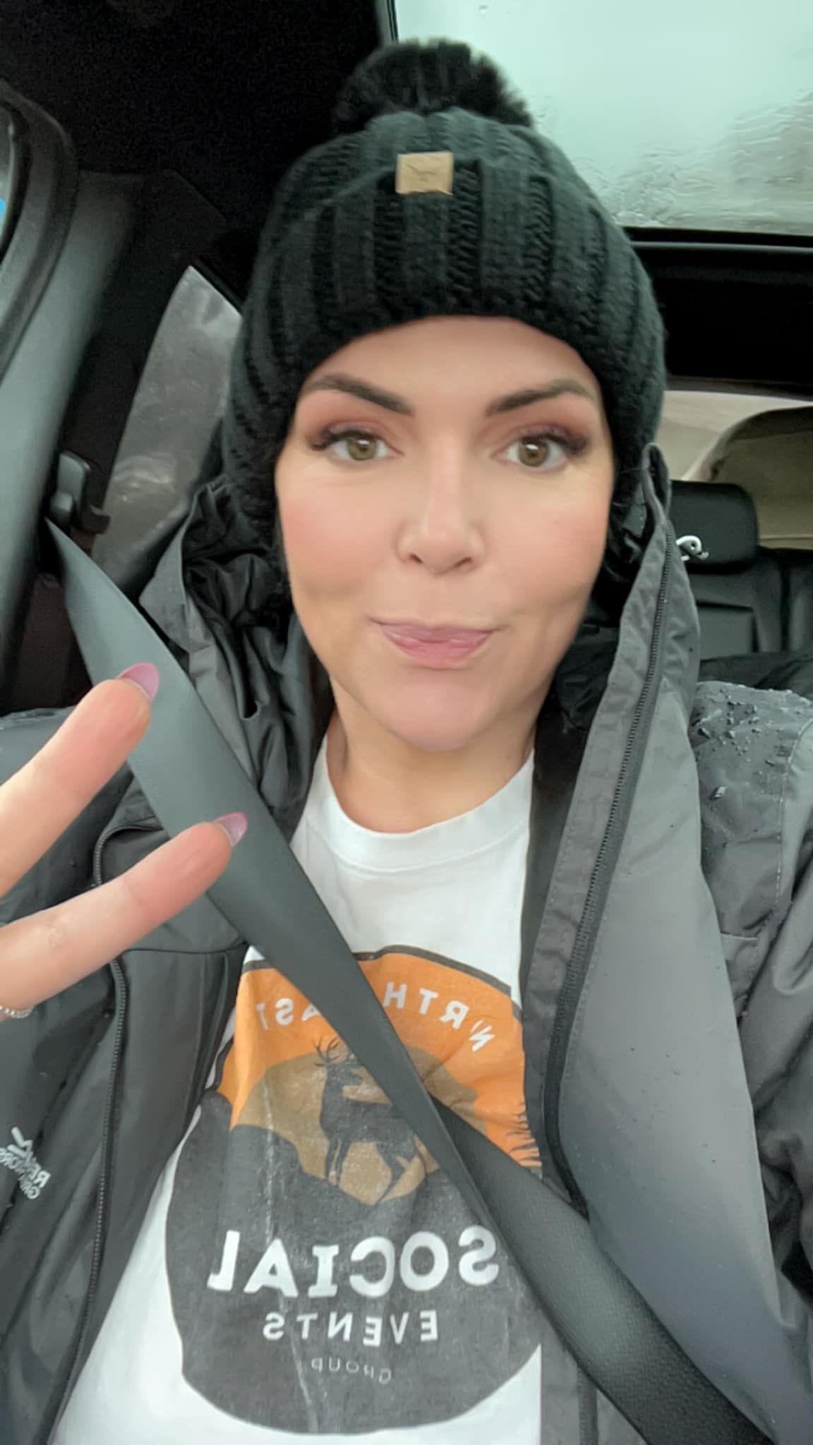 A woman wearing a black hat and a t-shirt is sitting in a car.