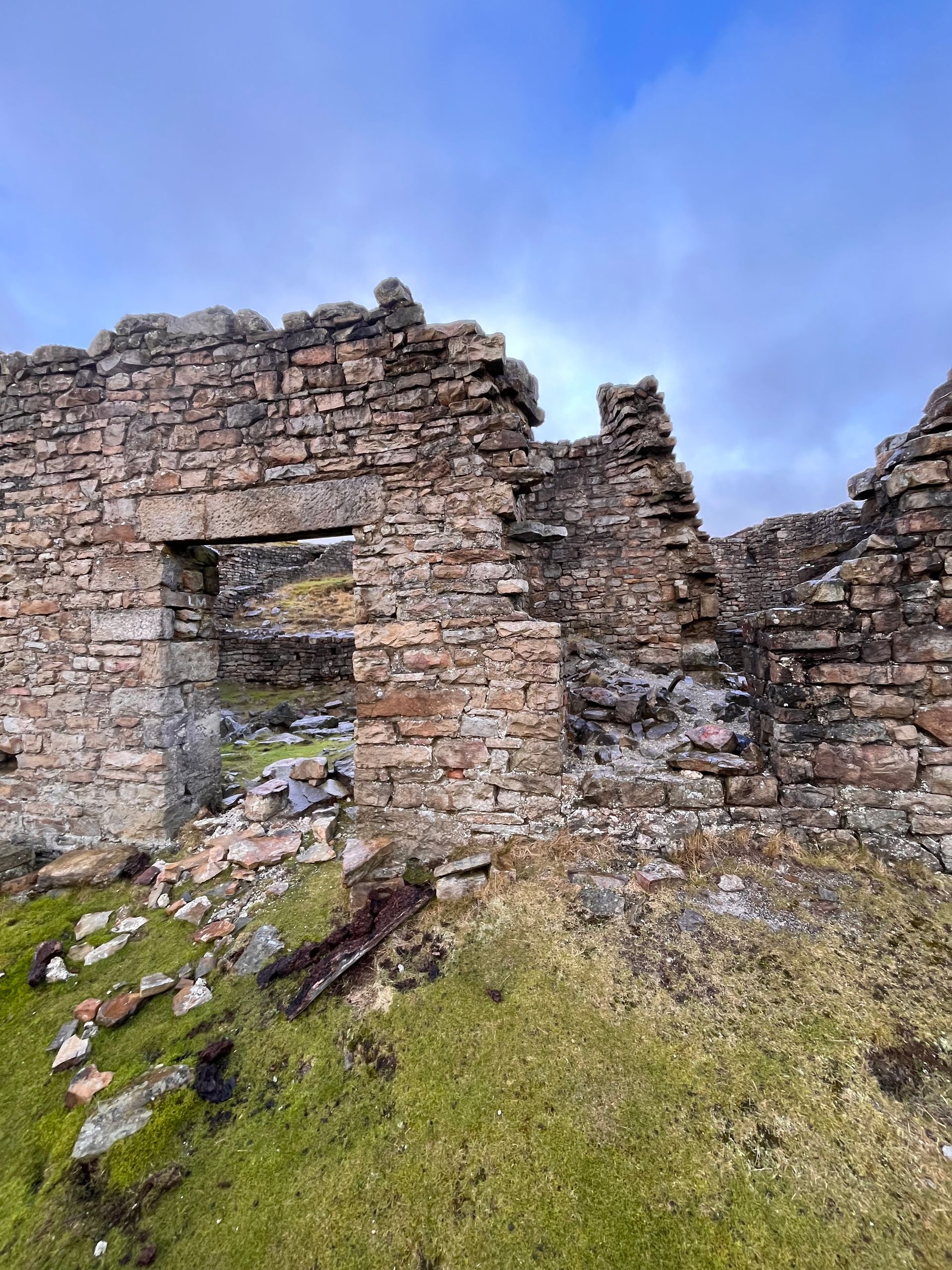 A brick building is sitting on top of a grassy hill.