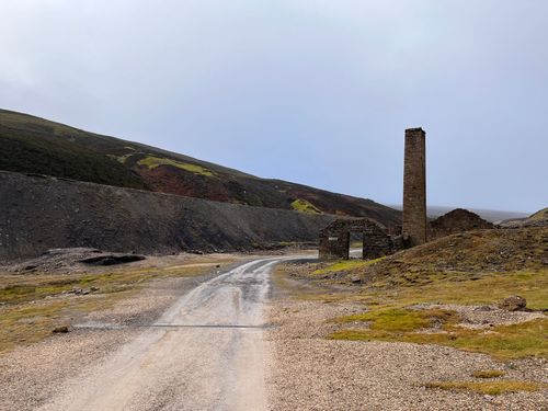 A dirt road with a chimney on the side of it.