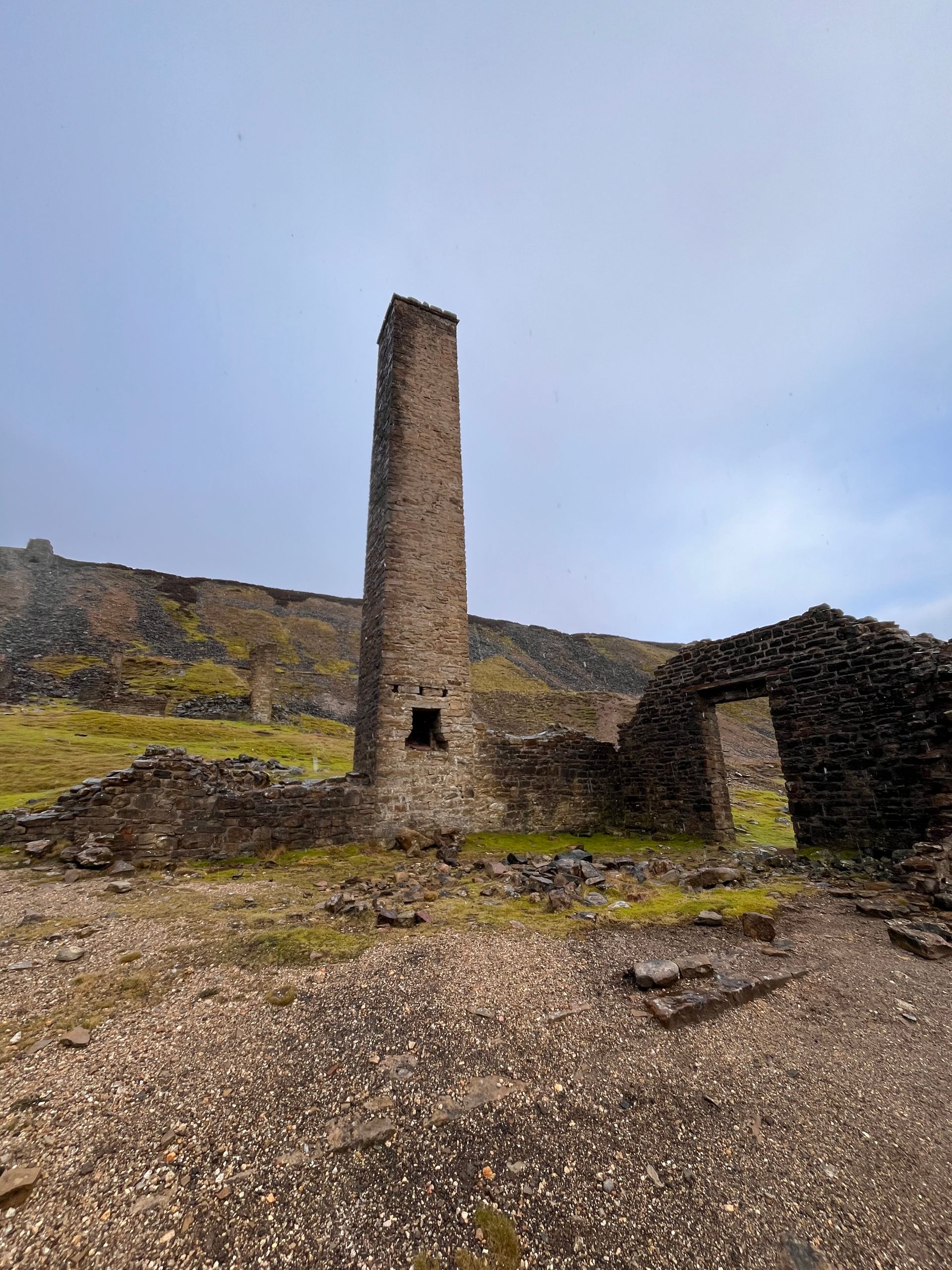 There is a very tall stone tower in the middle of a field.