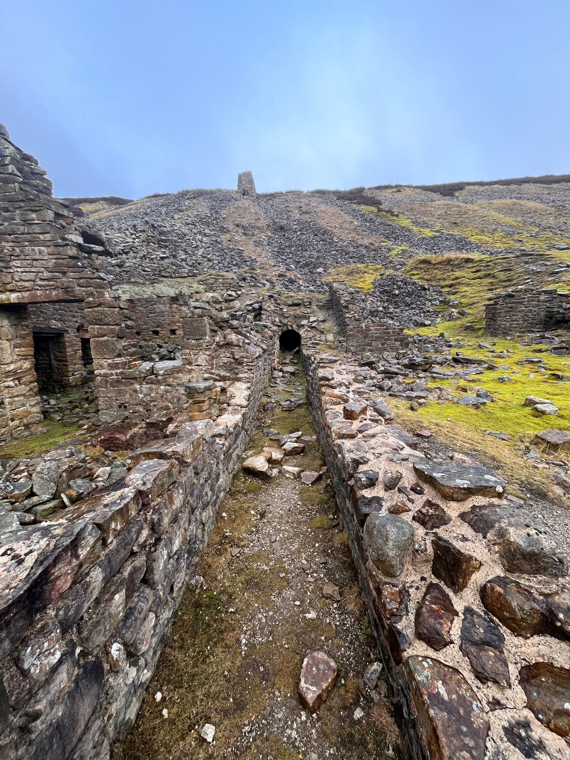A stone wall leading to a building on top of a hill.