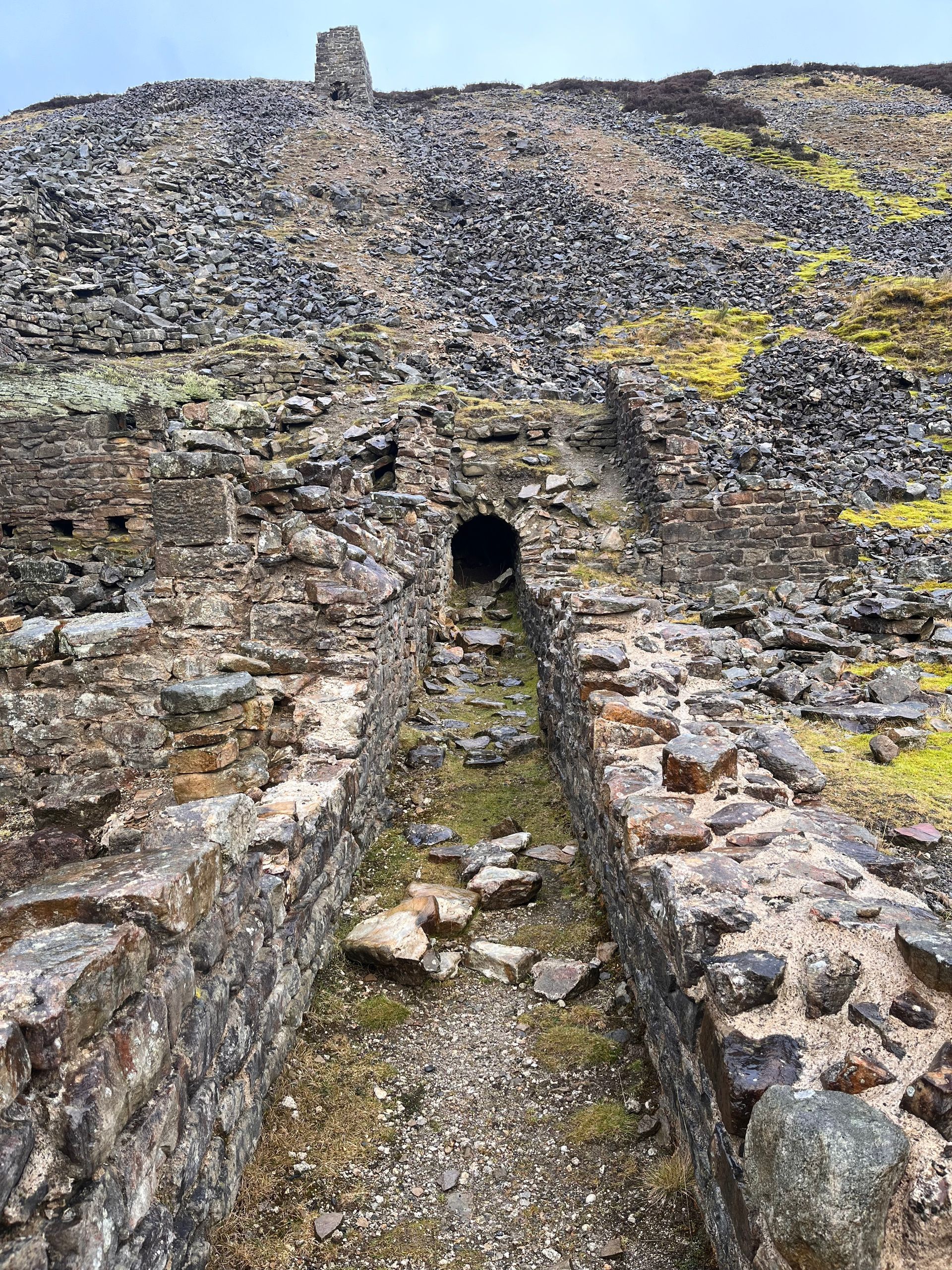 A stone wall with a tunnel going through it on top of a hill.