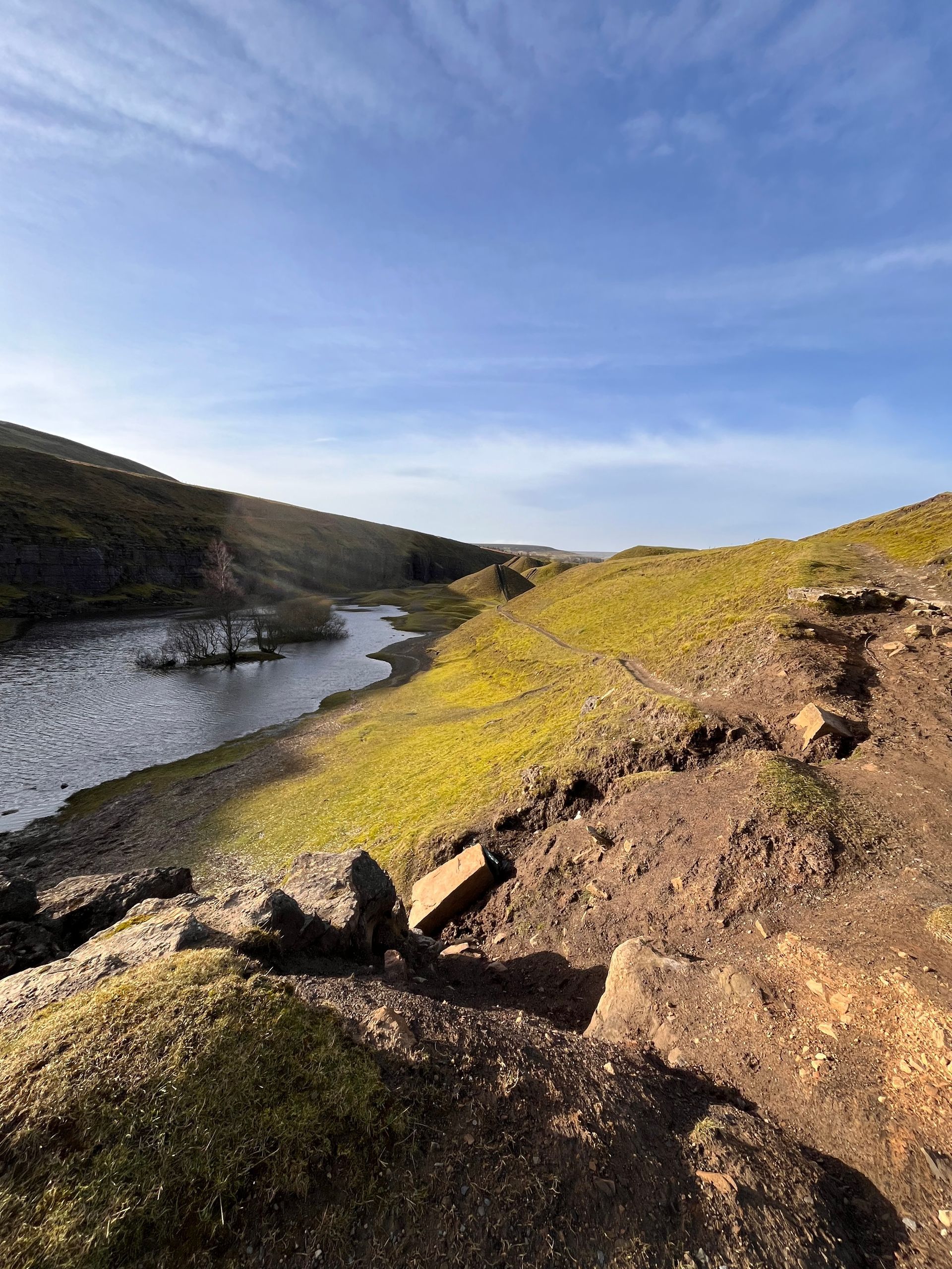 A river runs through a grassy hillside next to a river.