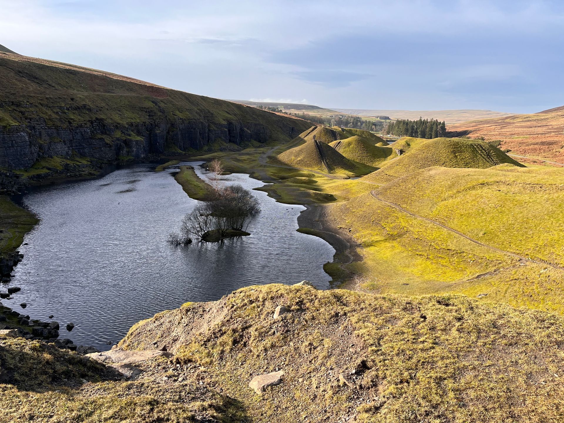 A river running through a valley surrounded by mountains and grass.