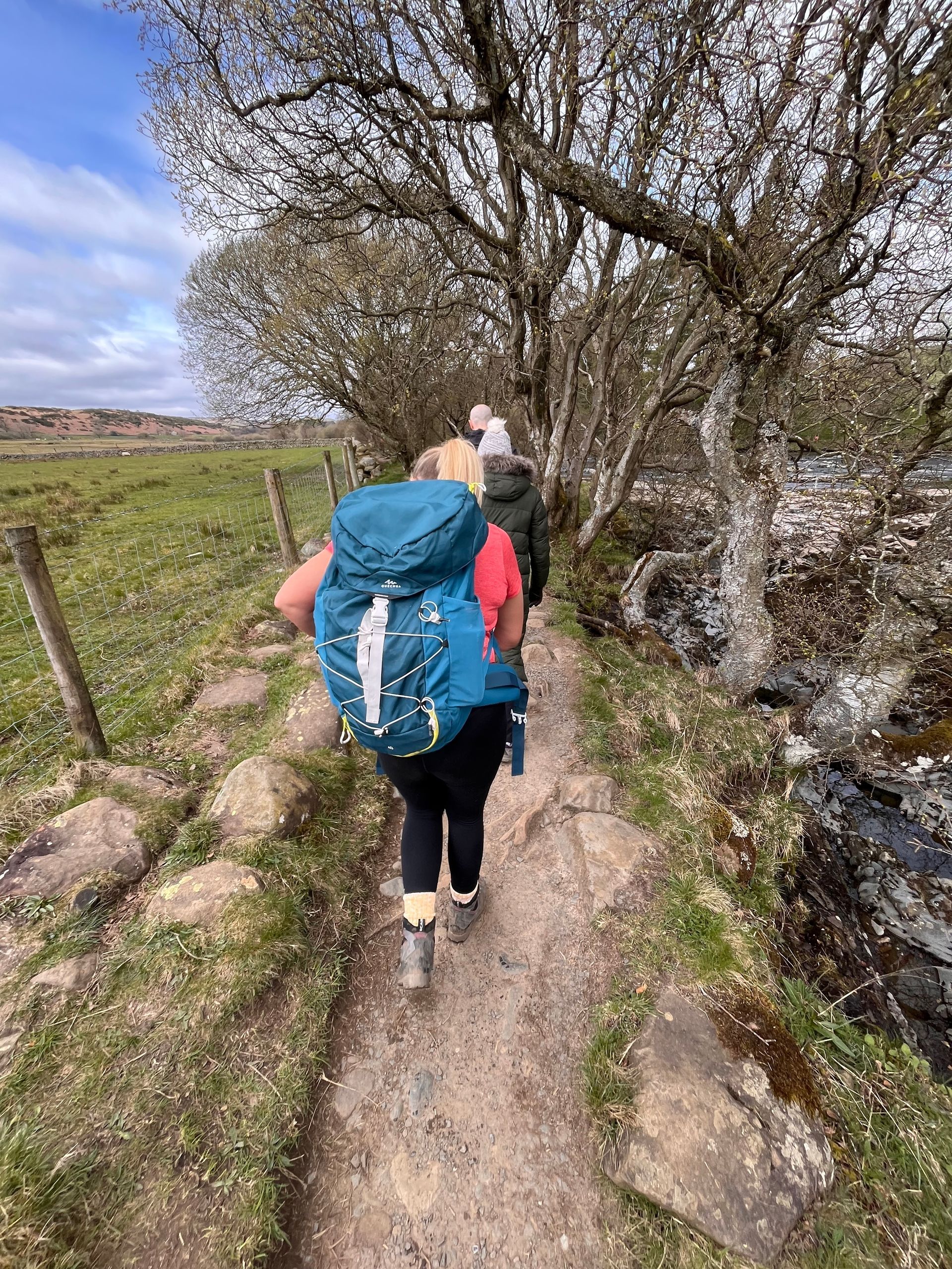 A group of people are walking down a dirt path.