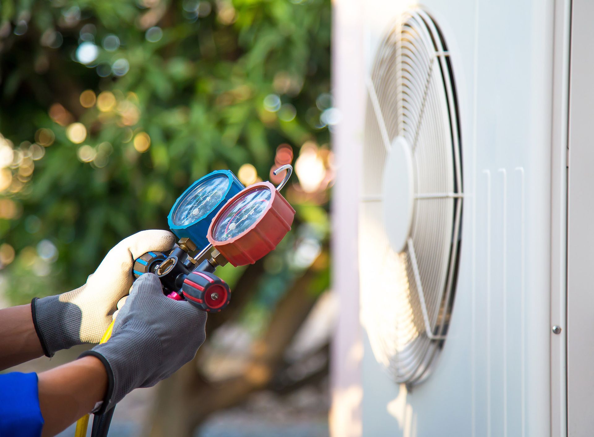 HVAC technician using gauges on an outdoor air conditioning unit.