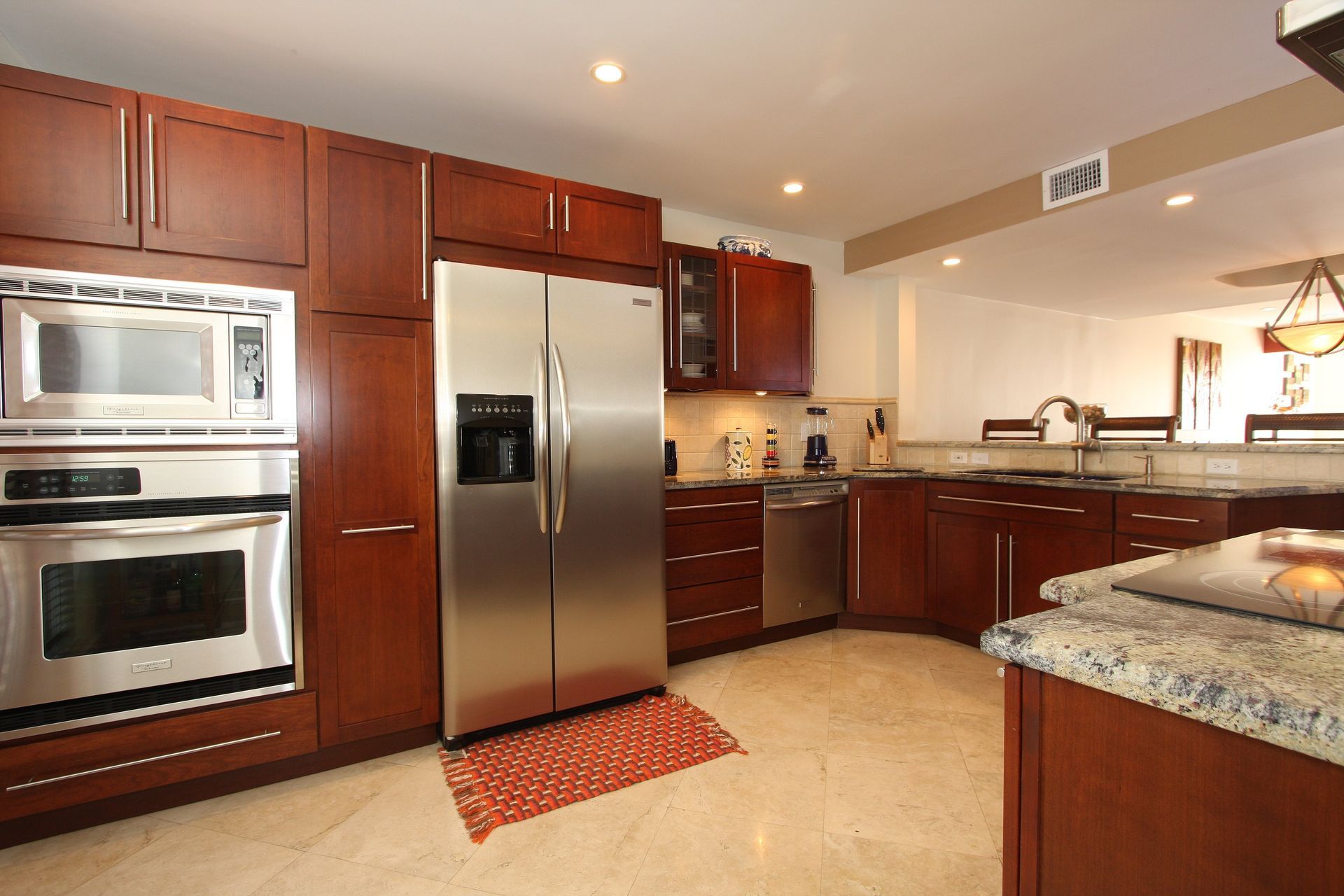 Stainless steel stove and ovens built into dark blue cabinets. Kitchen with marble backsplash.