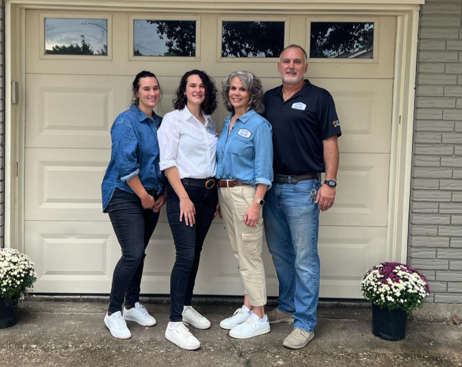 A group of people standing in front of a garage door.