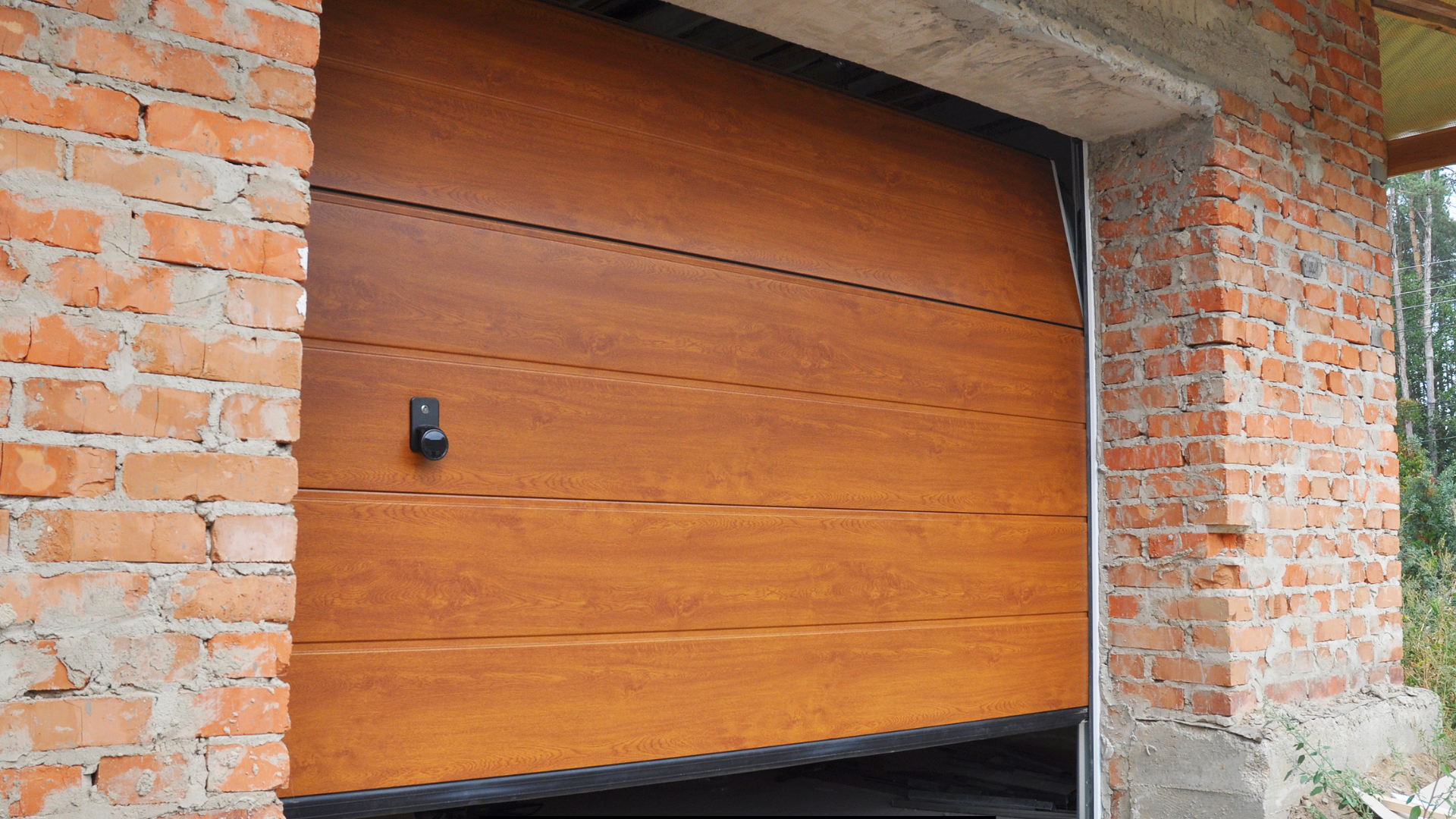 A wooden garage door is open in a brick building.