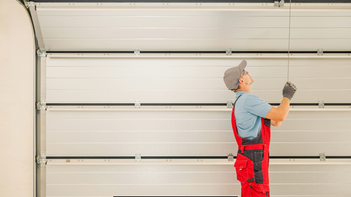 A man is writing on a clipboard while standing next to a garage door.