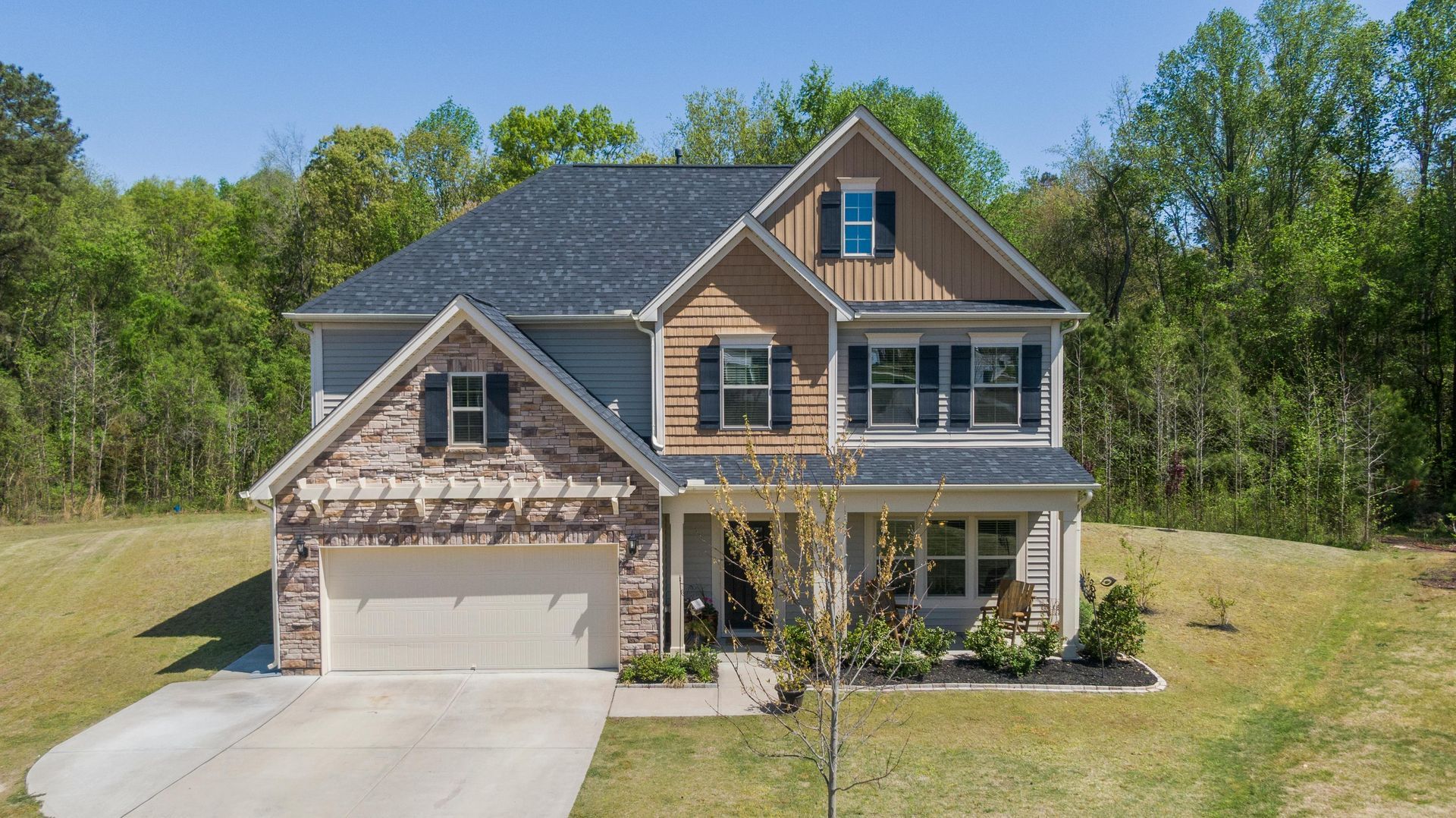 An aerial view of a house with a driveway and trees in the background