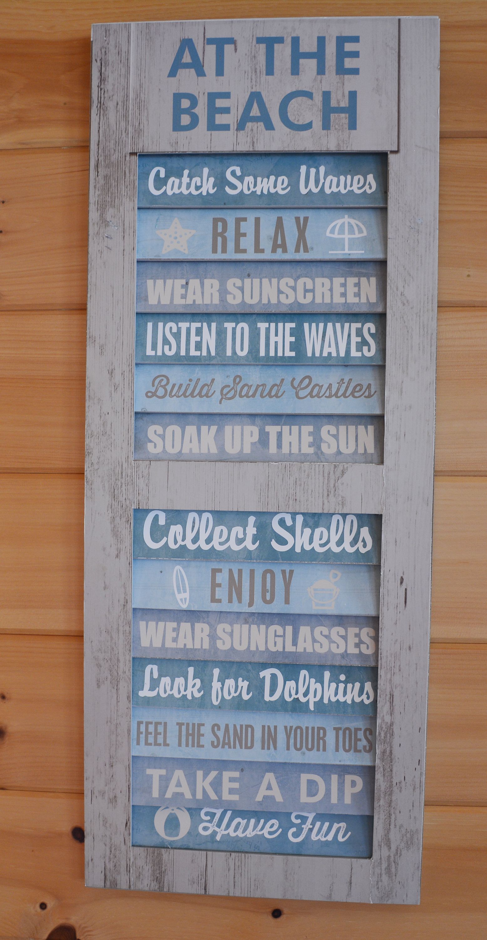 Wooden beach-themed sign with phrases in blue: 