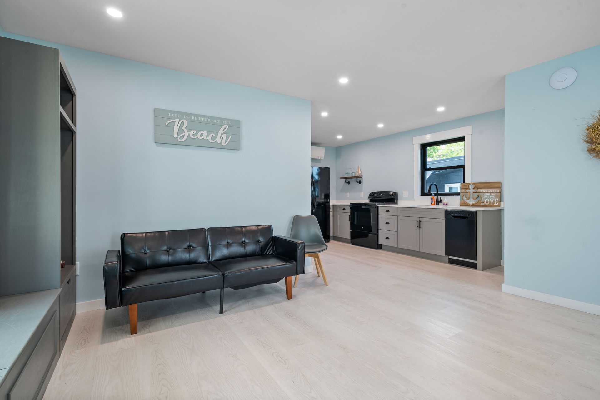Living room with a black couch, light blue walls, and gray cabinets.