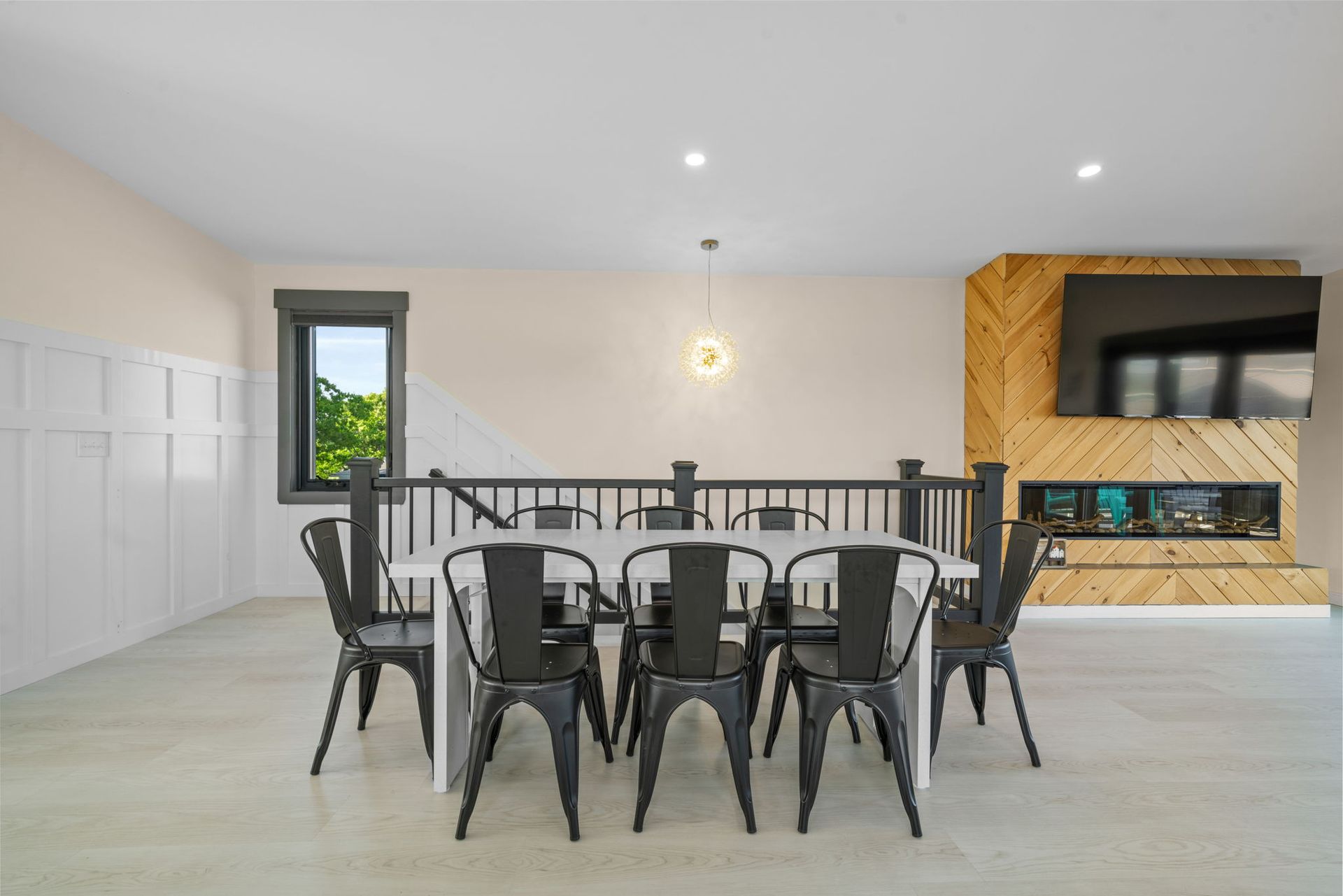 Dining room with white table, black chairs, and fireplace with TV.