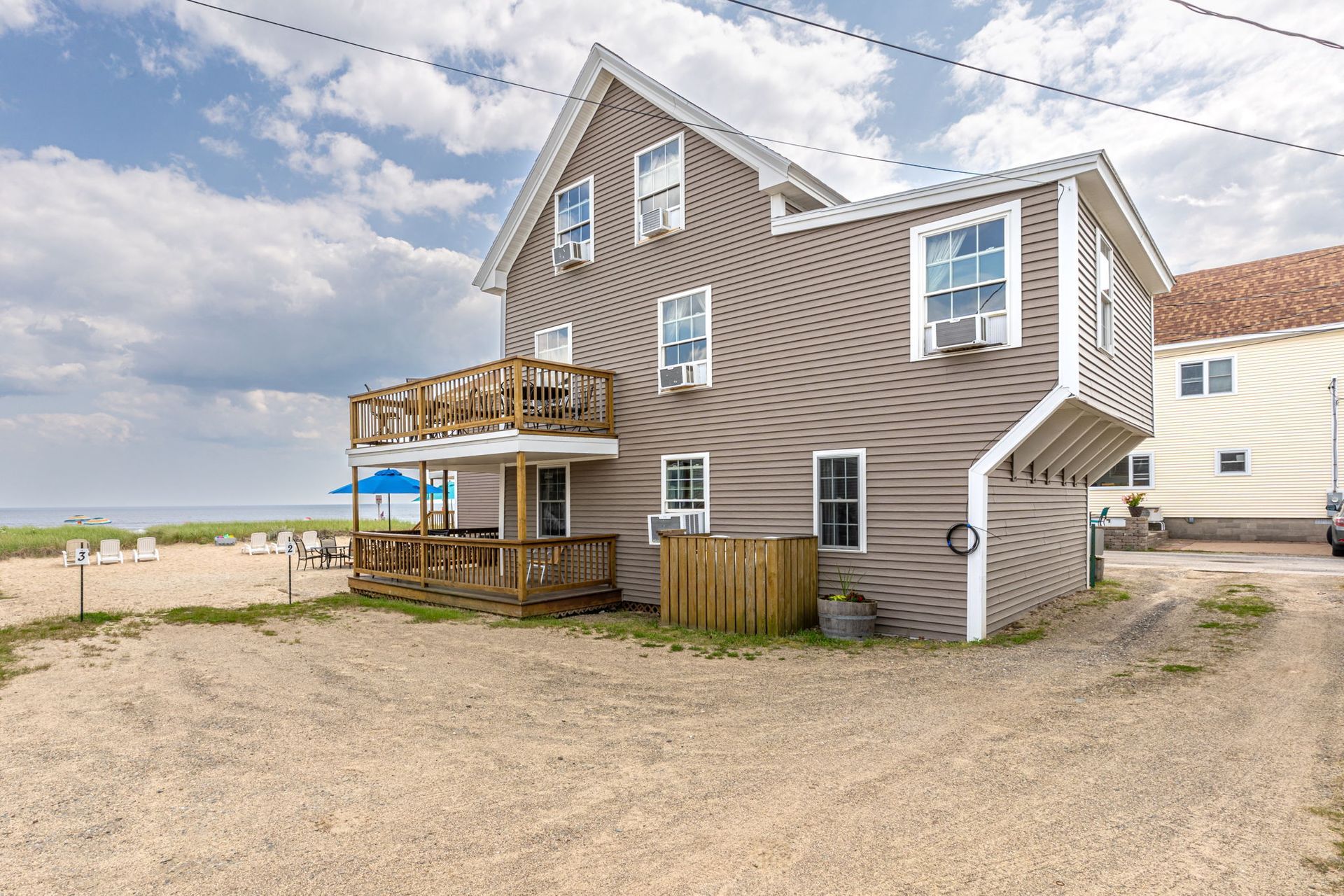 Beach house with gray siding, deck, and ocean view.