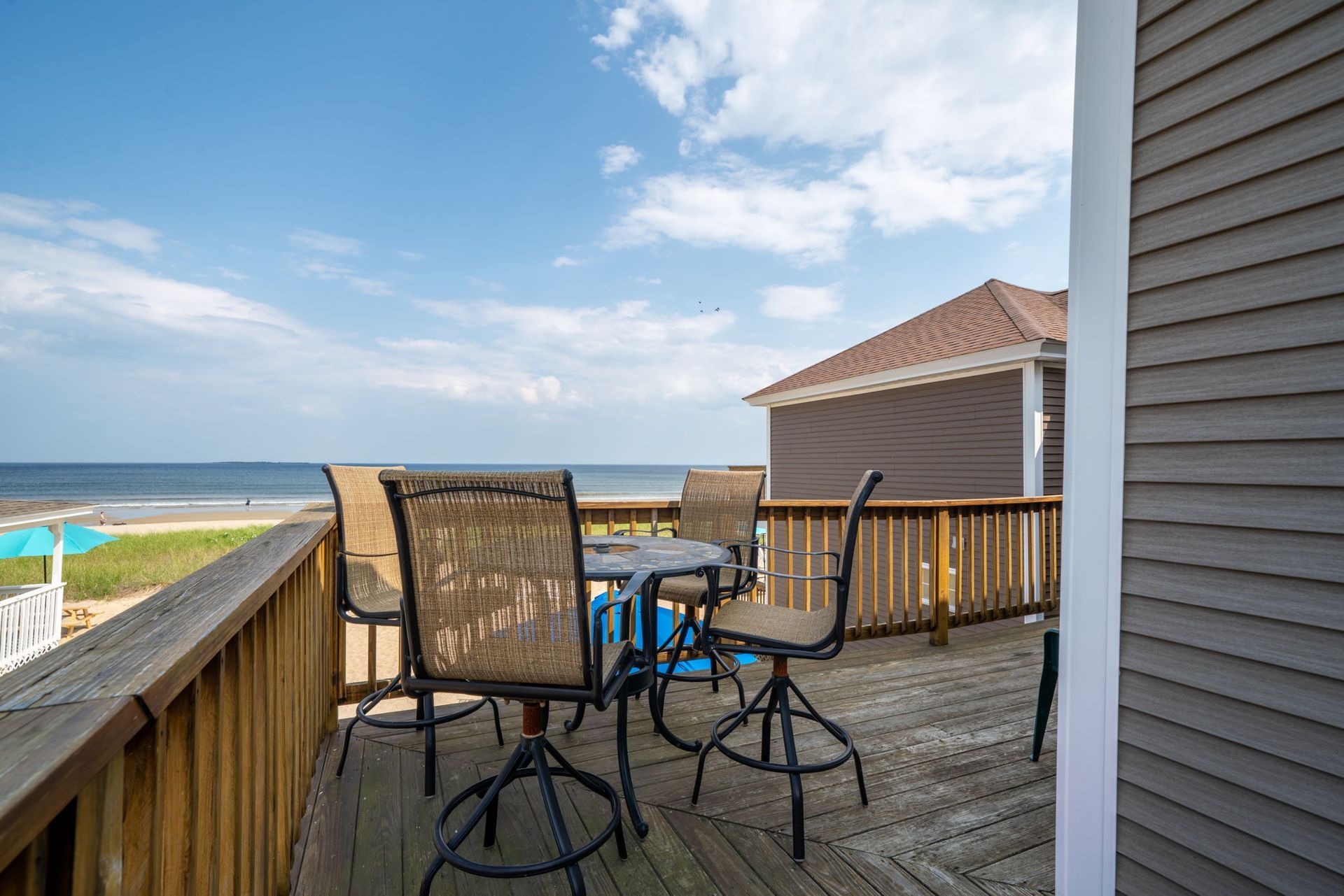 Deck with table and chairs overlooking the ocean on a sunny day.