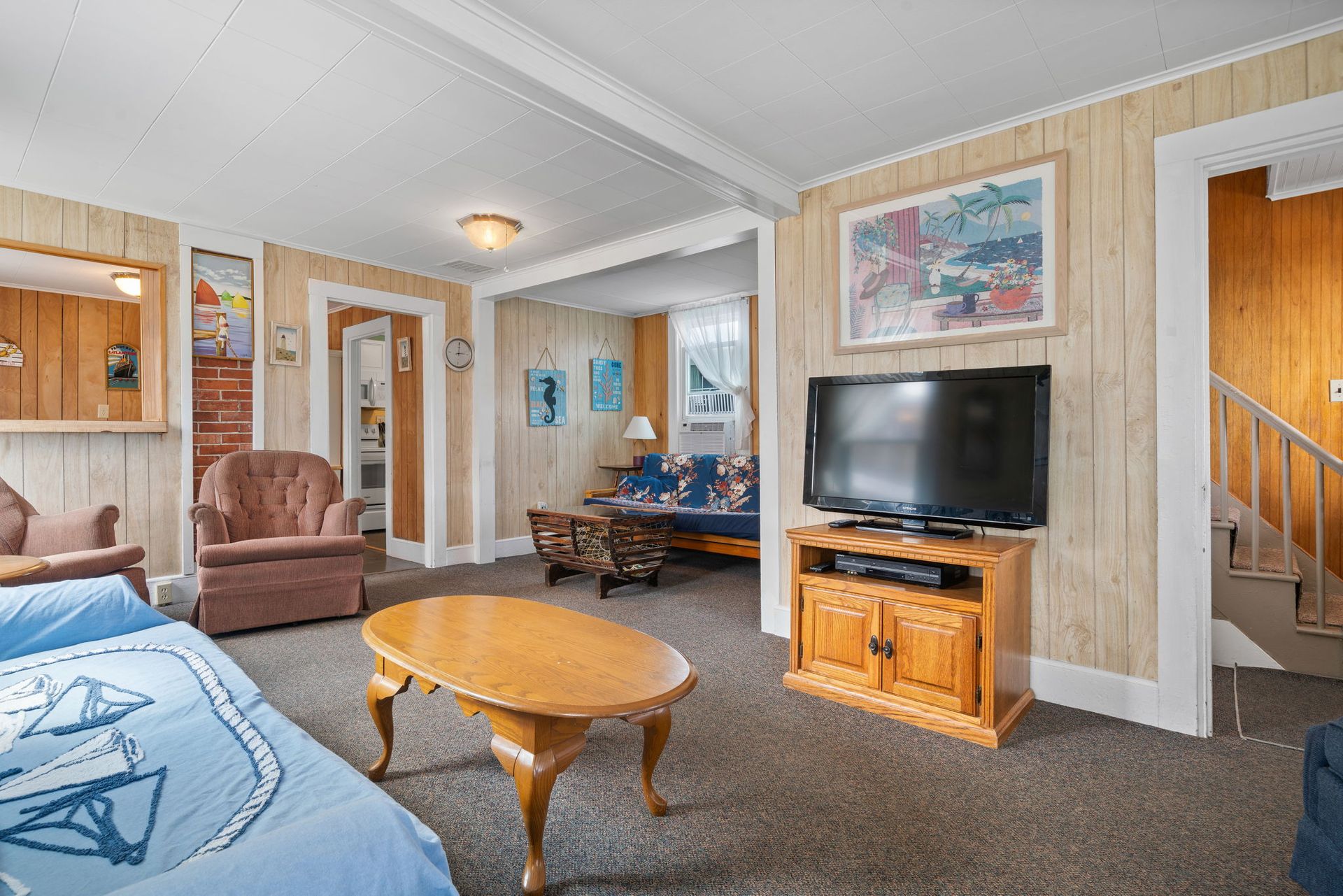 Cozy living room with wood paneling, TV on a wooden stand, and a nautical theme.