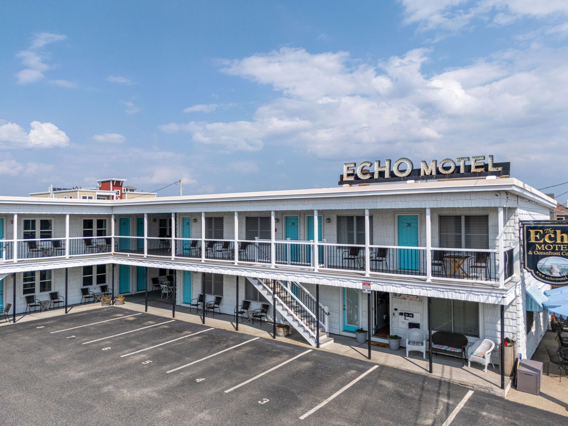 Echo Motel exterior, white building with teal doors, parking lot in front.
