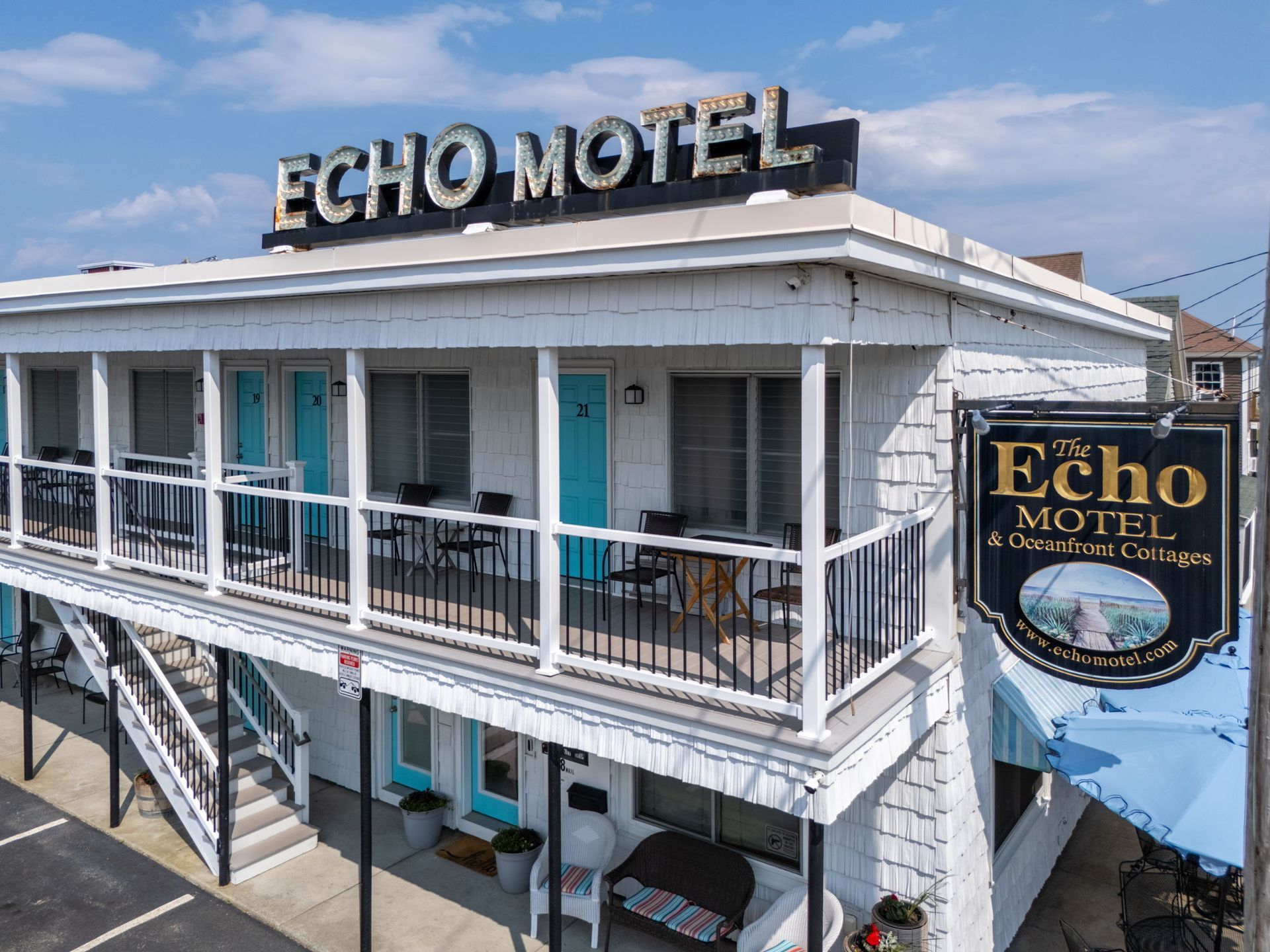 Echo Motel building with teal doors, white siding, a sign, and an ocean view.