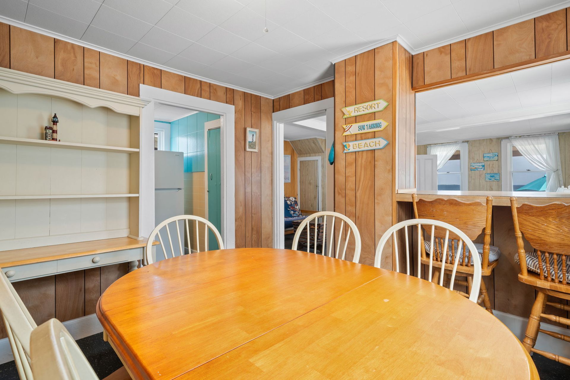Dining room with wooden table and chairs, wood paneling, and doorways.