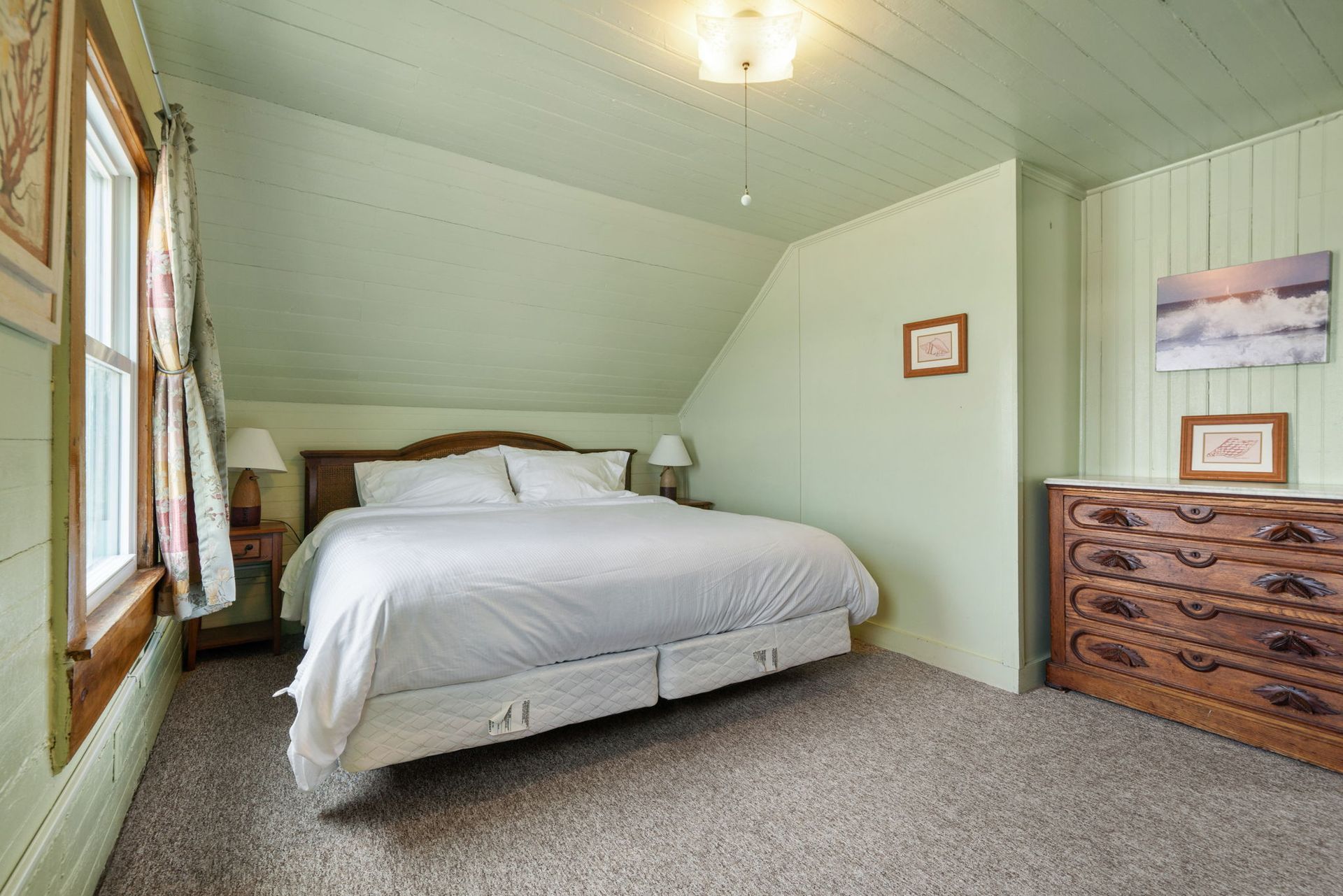 Bedroom with green walls, bed, dresser, window.