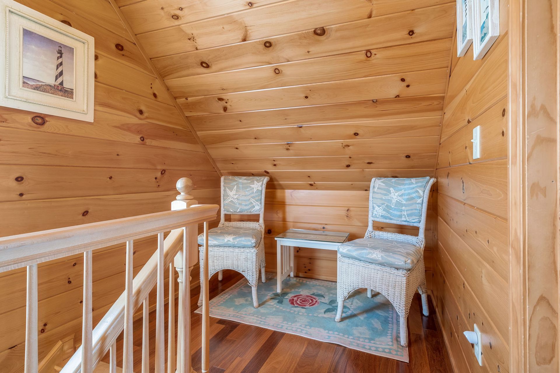 Cozy attic seating area with wicker chairs, small table, and wooden walls.