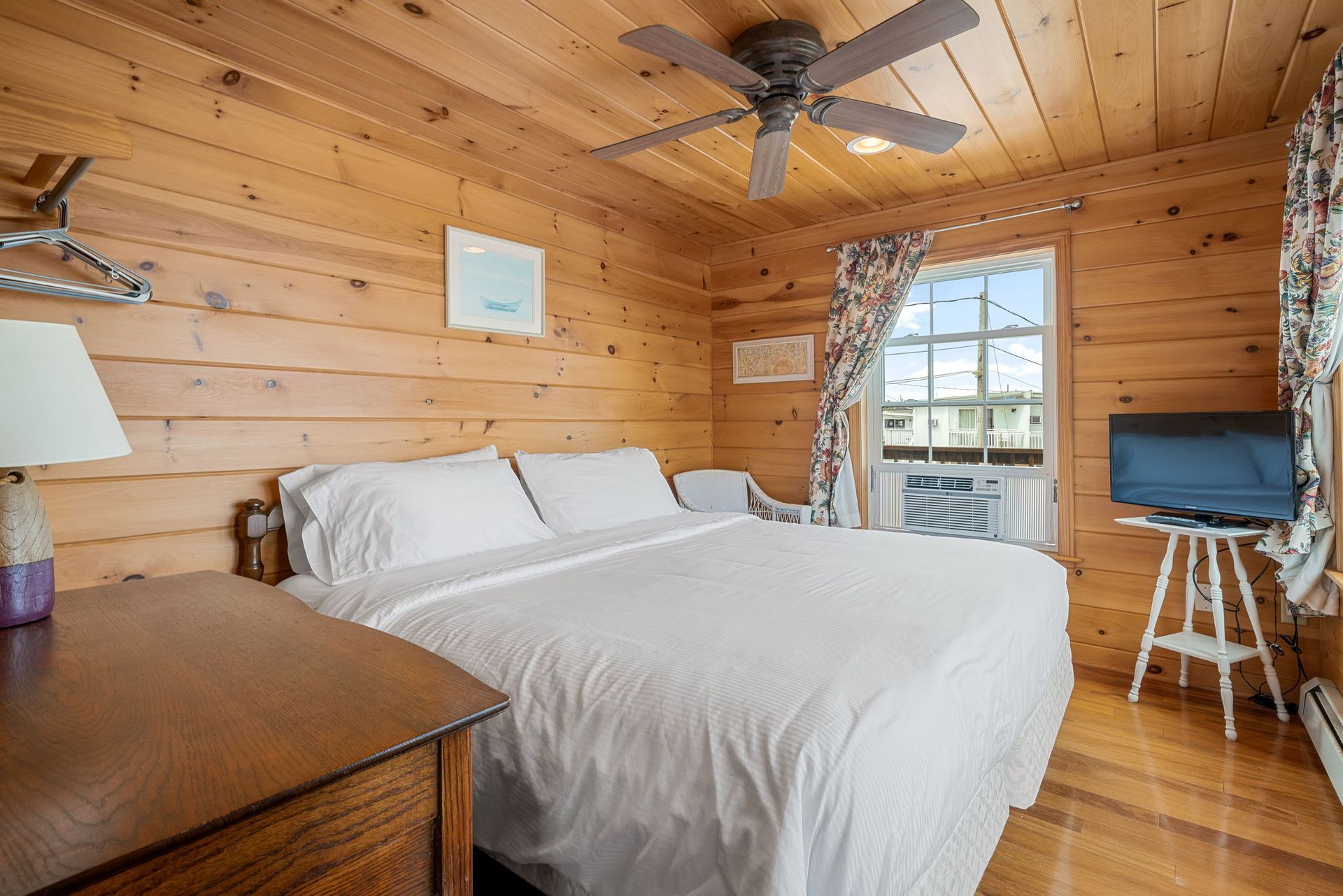 Bedroom with wood paneling, queen bed, and a small window.