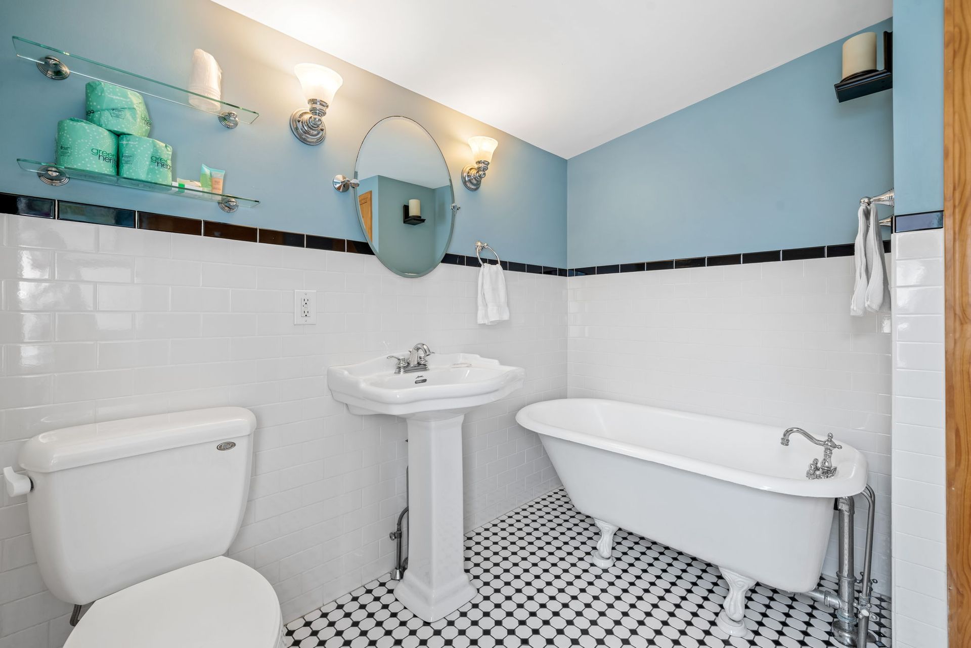 Bathroom with white tiled walls, blue upper walls, pedestal sink, and clawfoot tub.