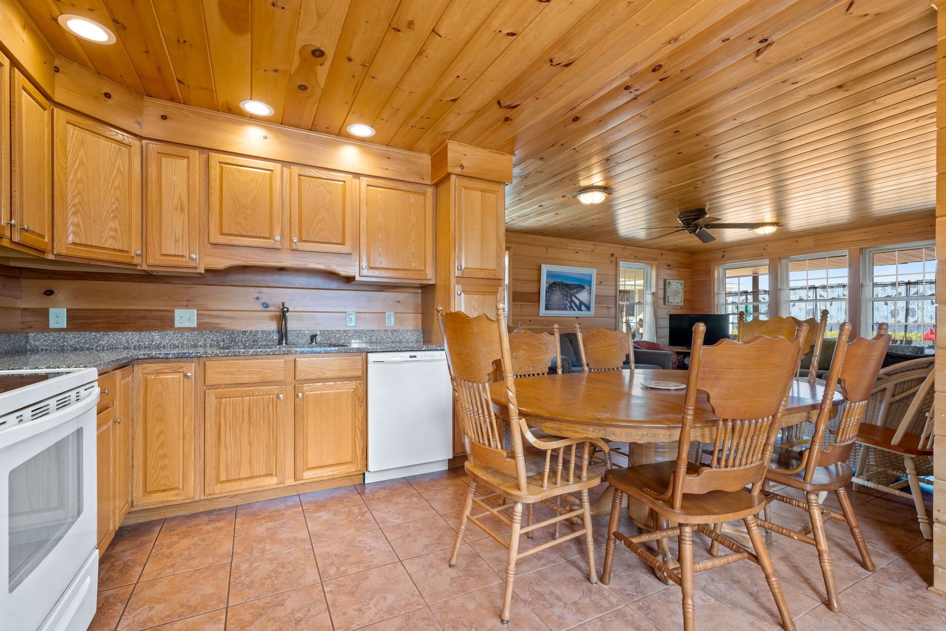 Kitchen with wooden cabinets, a round table with chairs, and a connected living area.