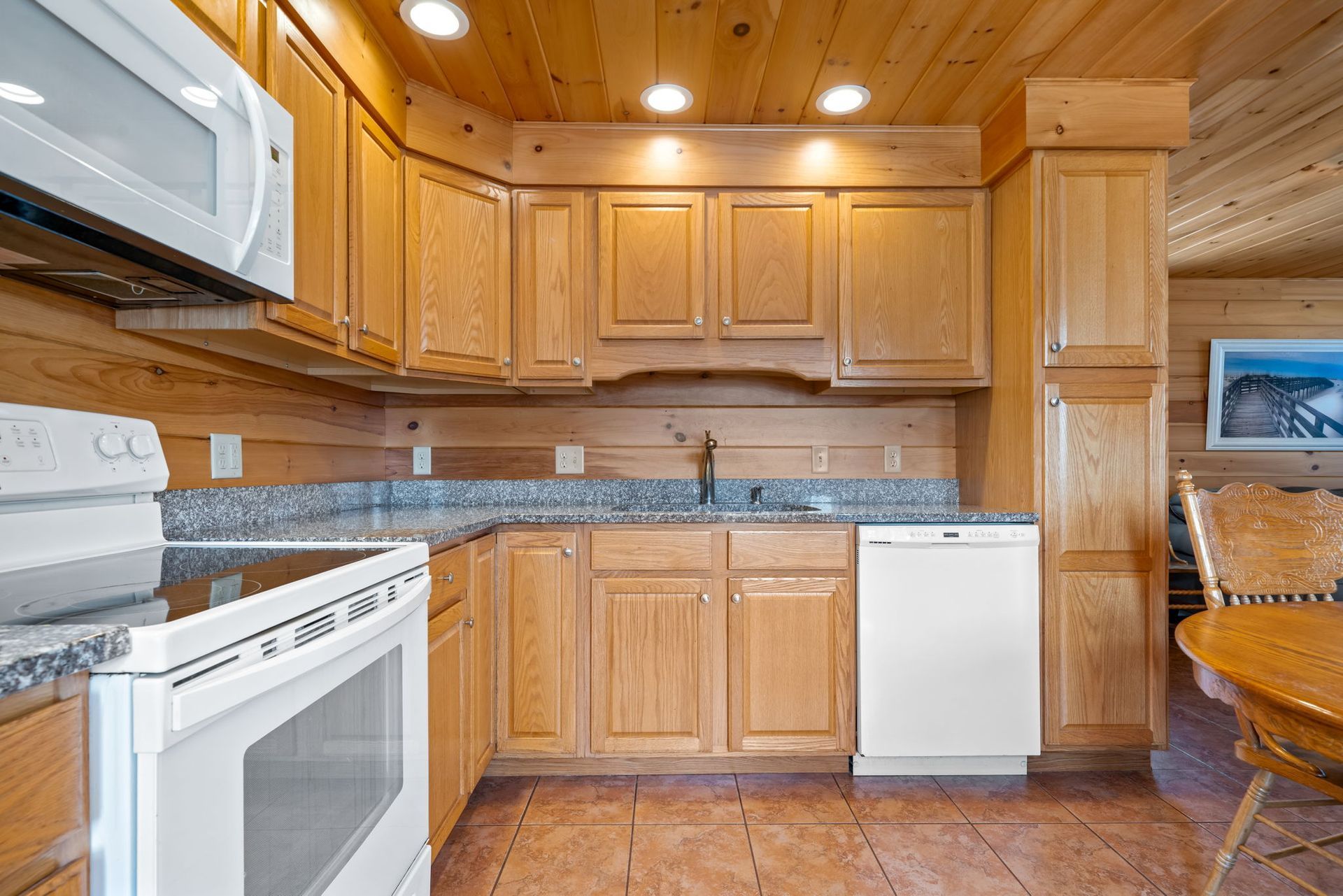 Kitchen with wooden cabinets, granite counters, and white appliances.