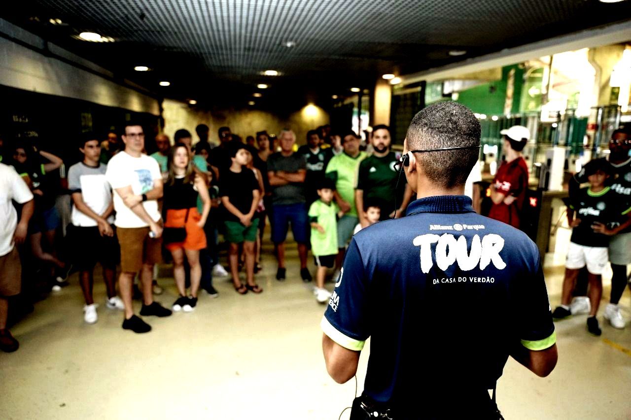 Um homem com uma camisa de turnê está em frente a uma multidão de pessoas