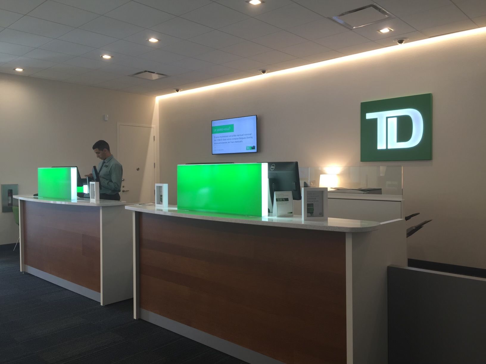 Un homme se tient debout au comptoir d'une banque TD
