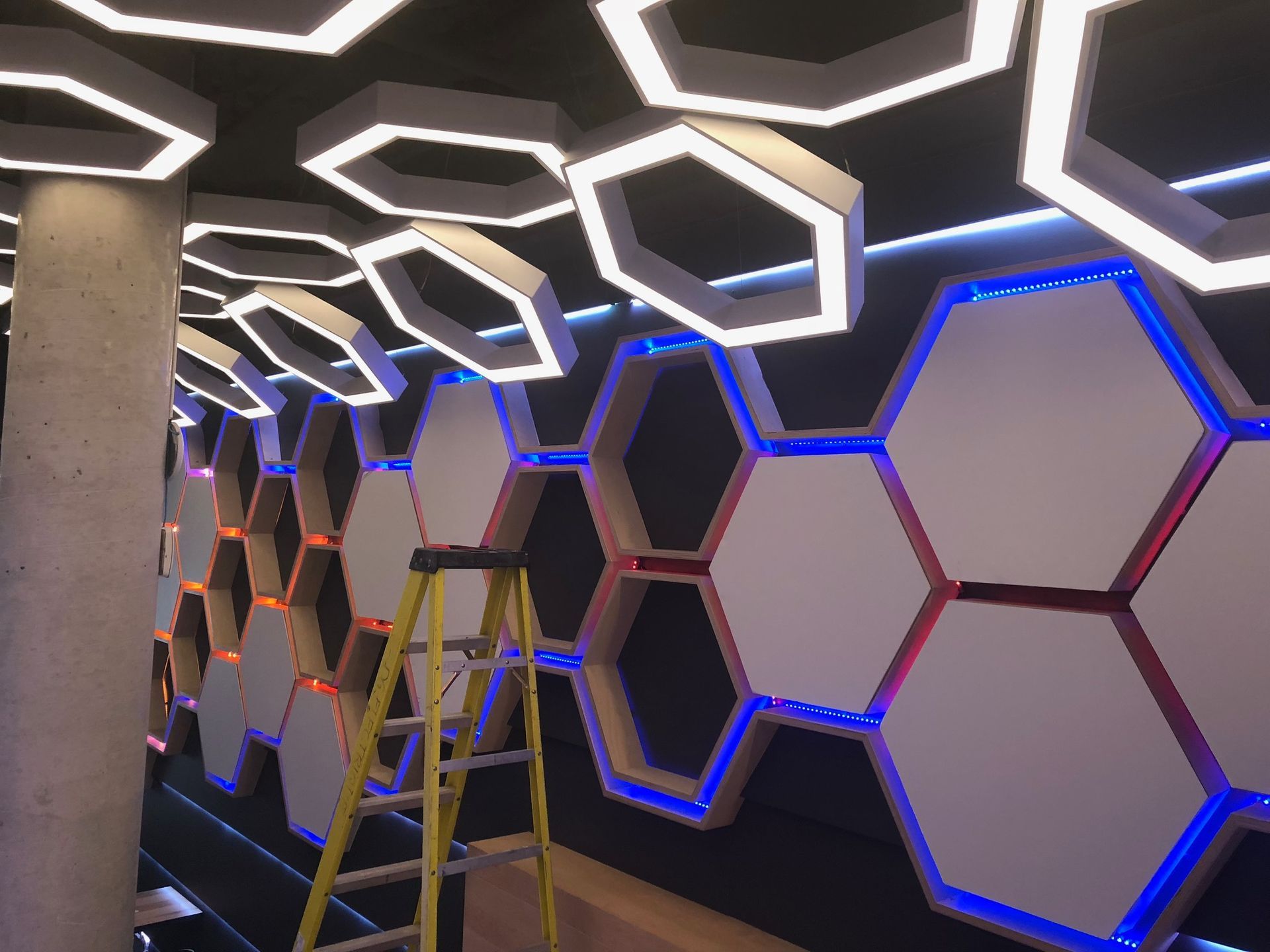 Une échelle est assise devant un mur avec des hexagones dessus