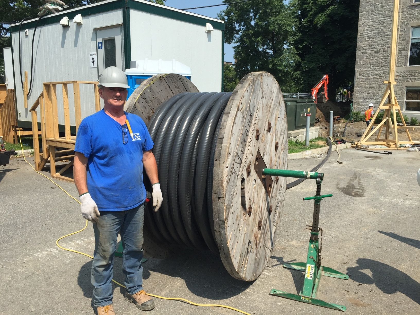 Un homme debout à côté d'une grande bobine de câble