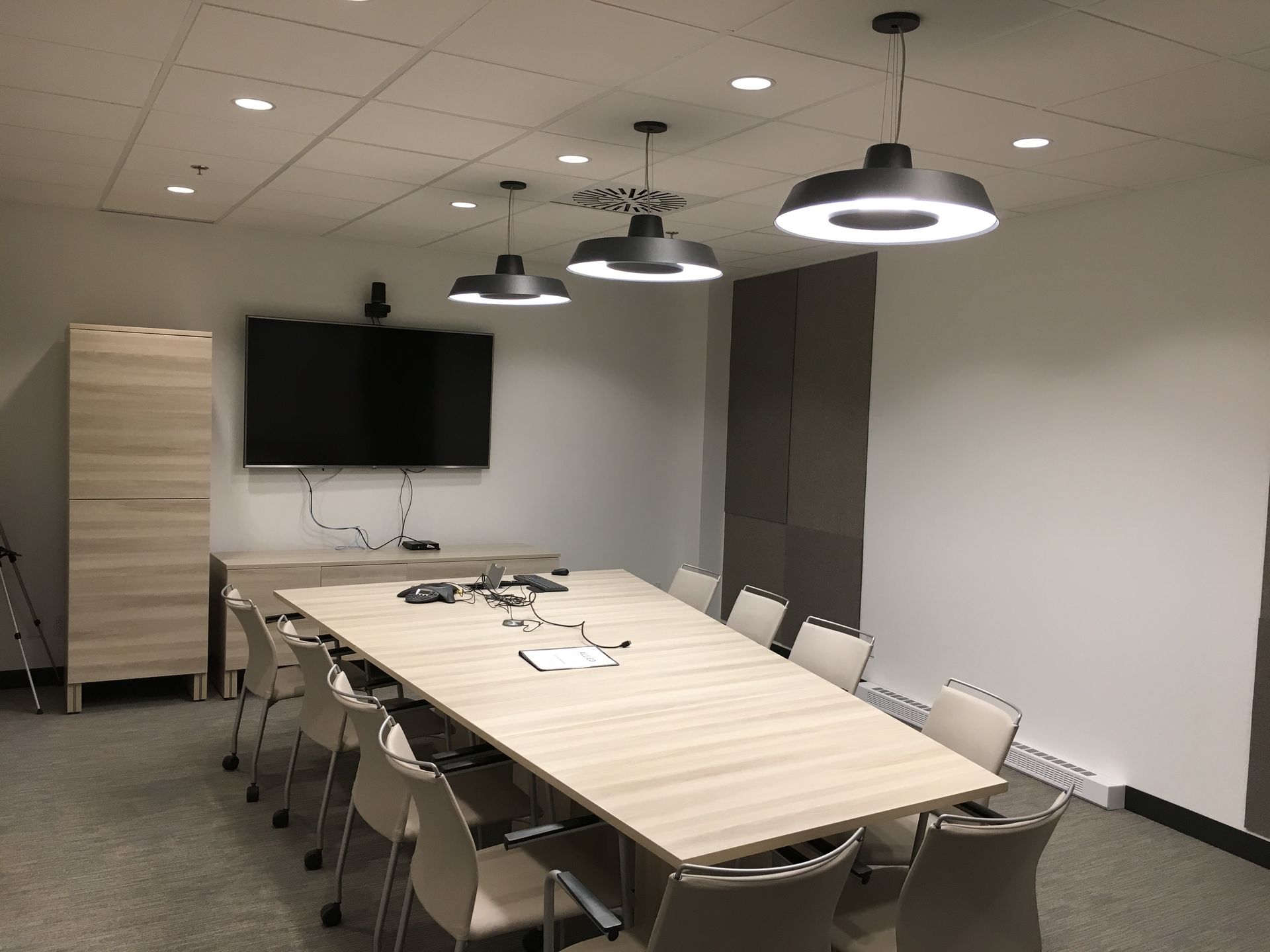 Une salle de conférence avec une longue table et des chaises et une télévision à écran plat.