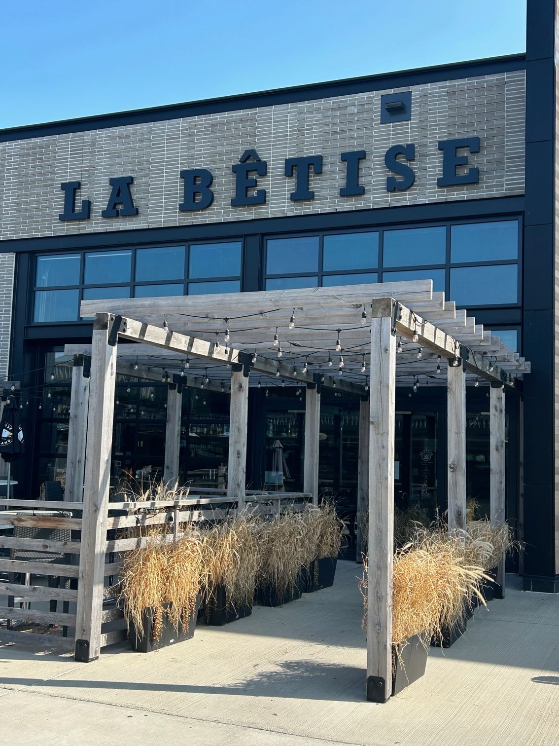 Un grand bâtiment en briques avec une pergola en bois devant.