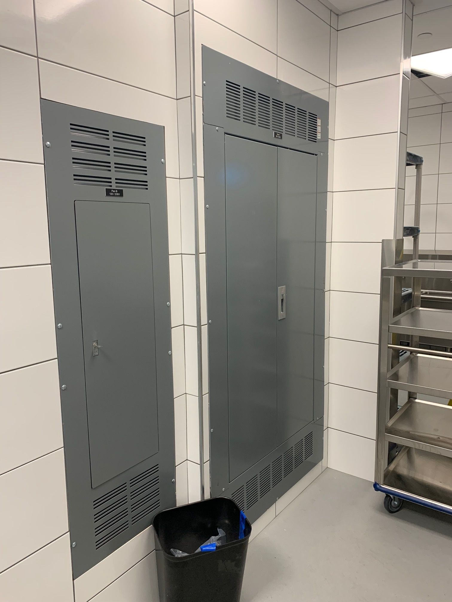 Une poubelle noire se trouve à côté d'une porte grise dans une pièce.