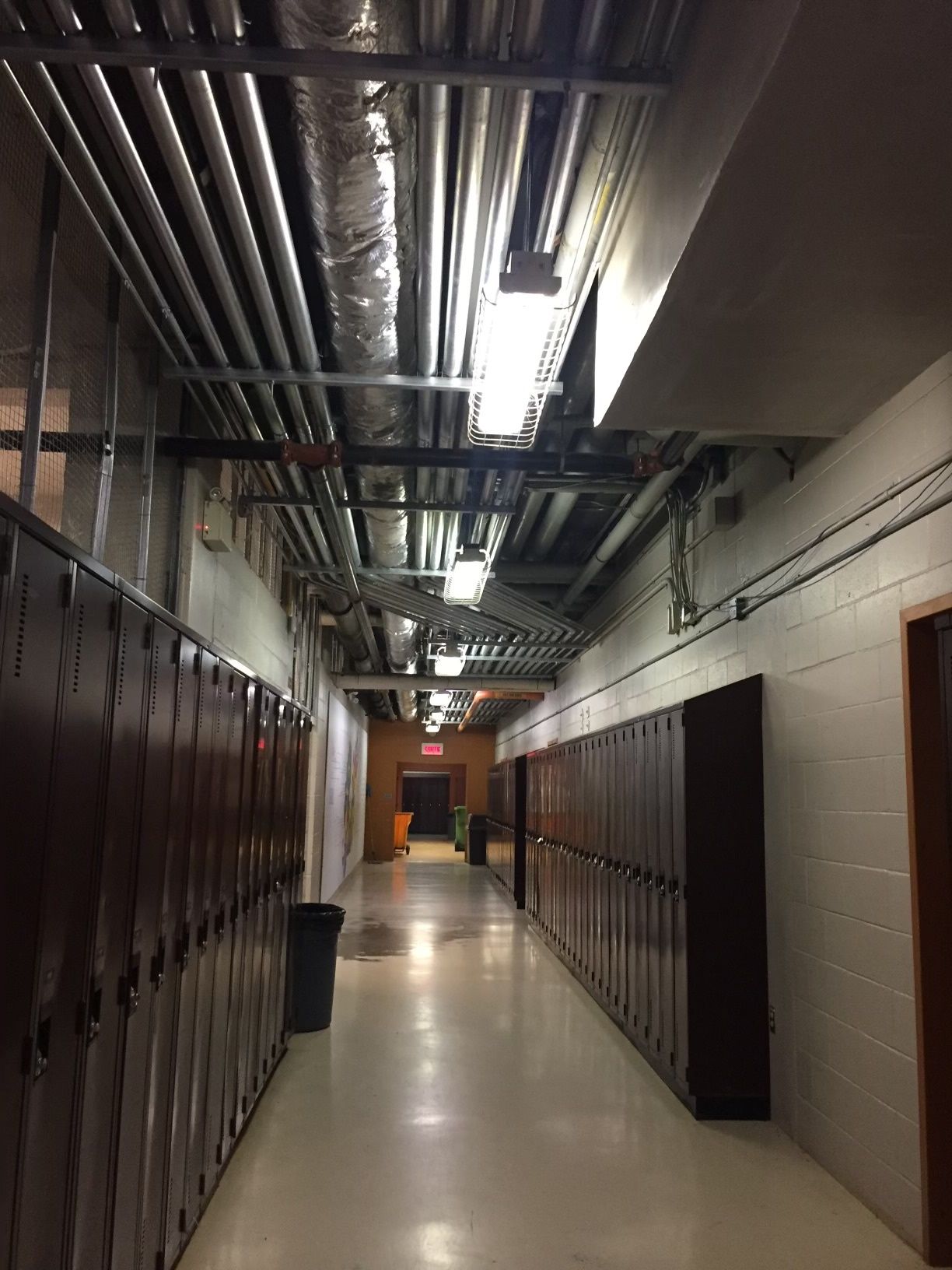 Un long couloir avec beaucoup de casiers et de tuyaux