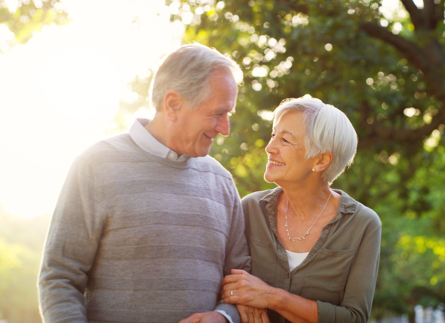 Smiling couple holding hands outdoors in warm sunlight