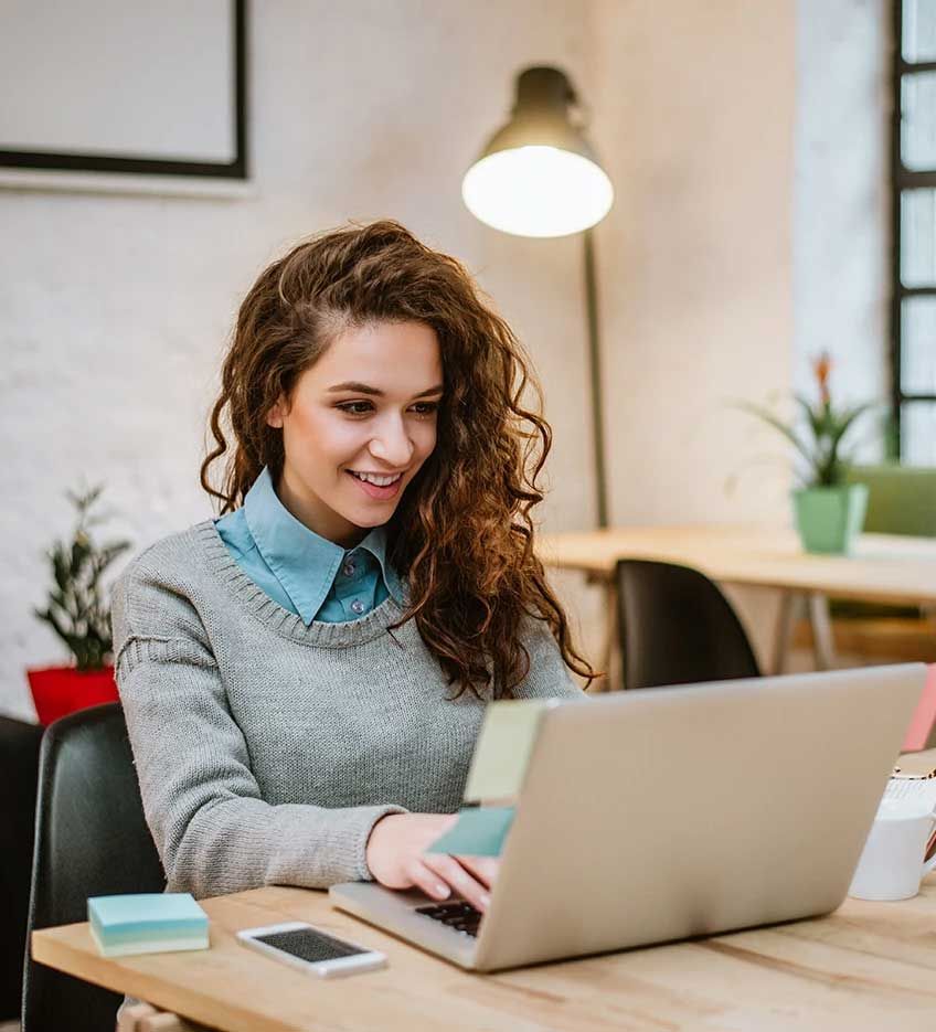 A woman is sitting at a desk using a laptop computer.