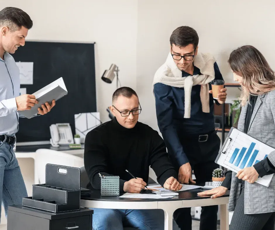 A group of people are standing around a table in an office.