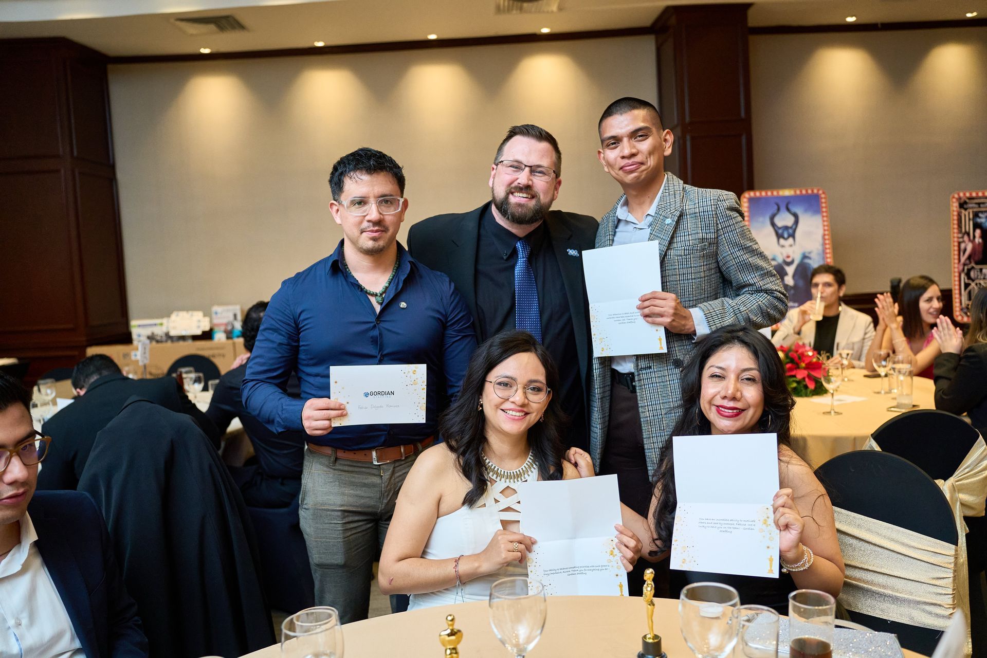 A group of people are sitting at a table holding papers.