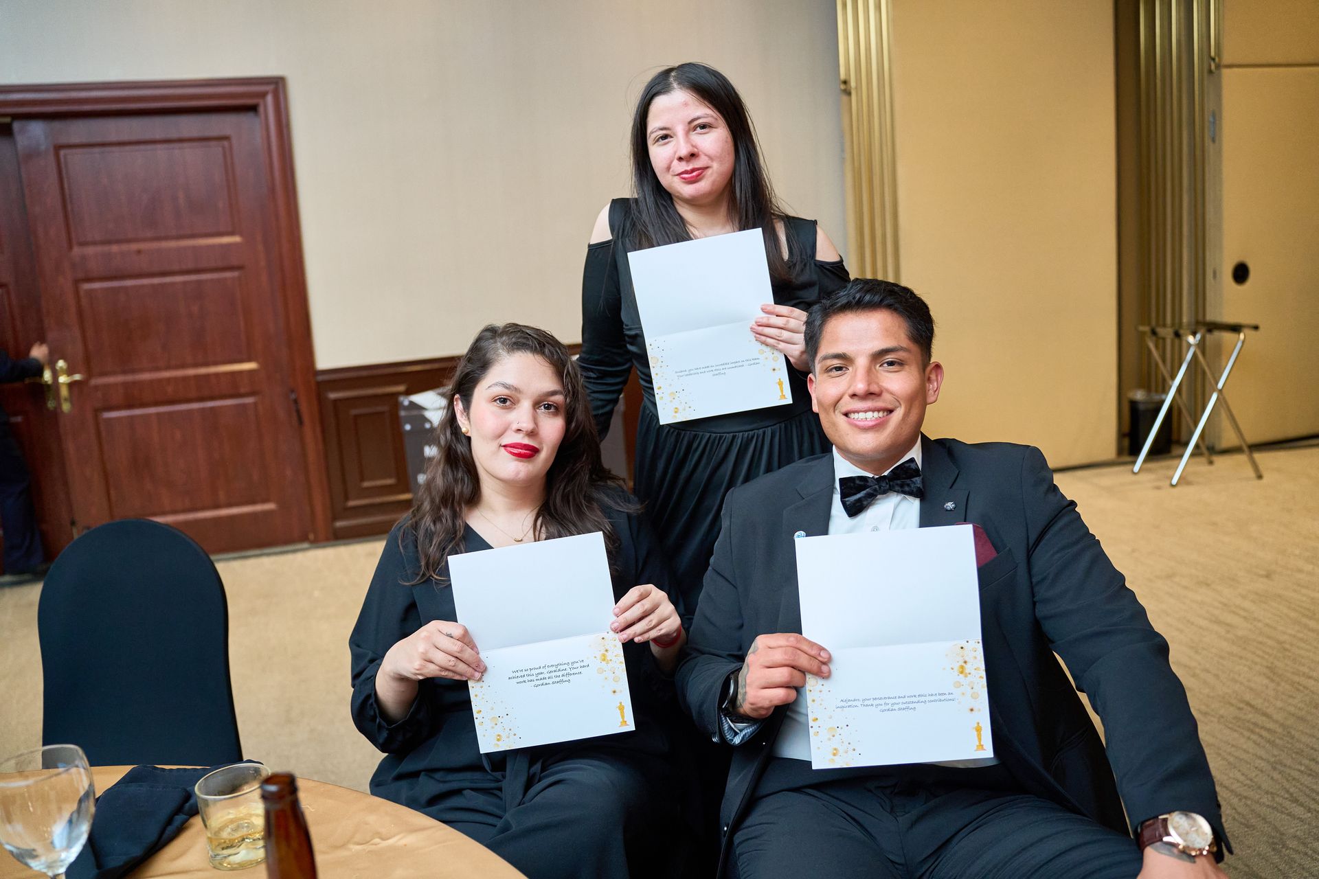 A man and two women are sitting at a table holding papers.