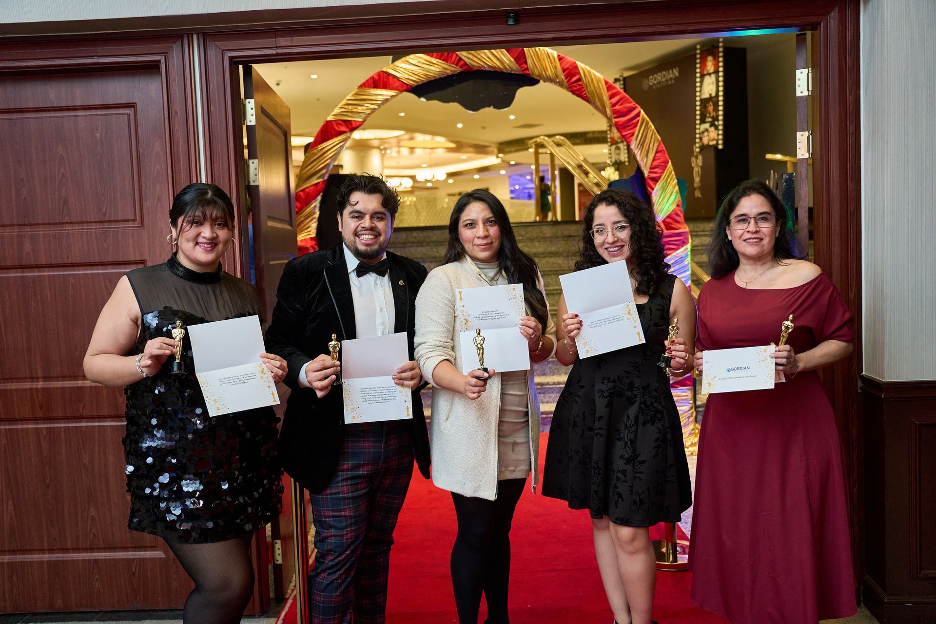 A group of people are standing on a red carpet holding awards.