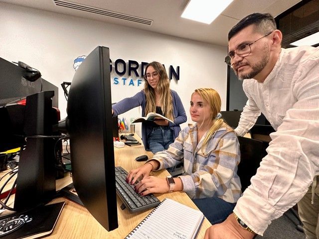 A man and two women are looking at a computer screen.