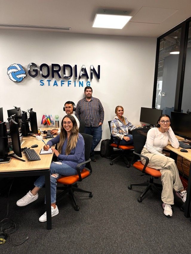 A group of people are sitting at desks in an office.